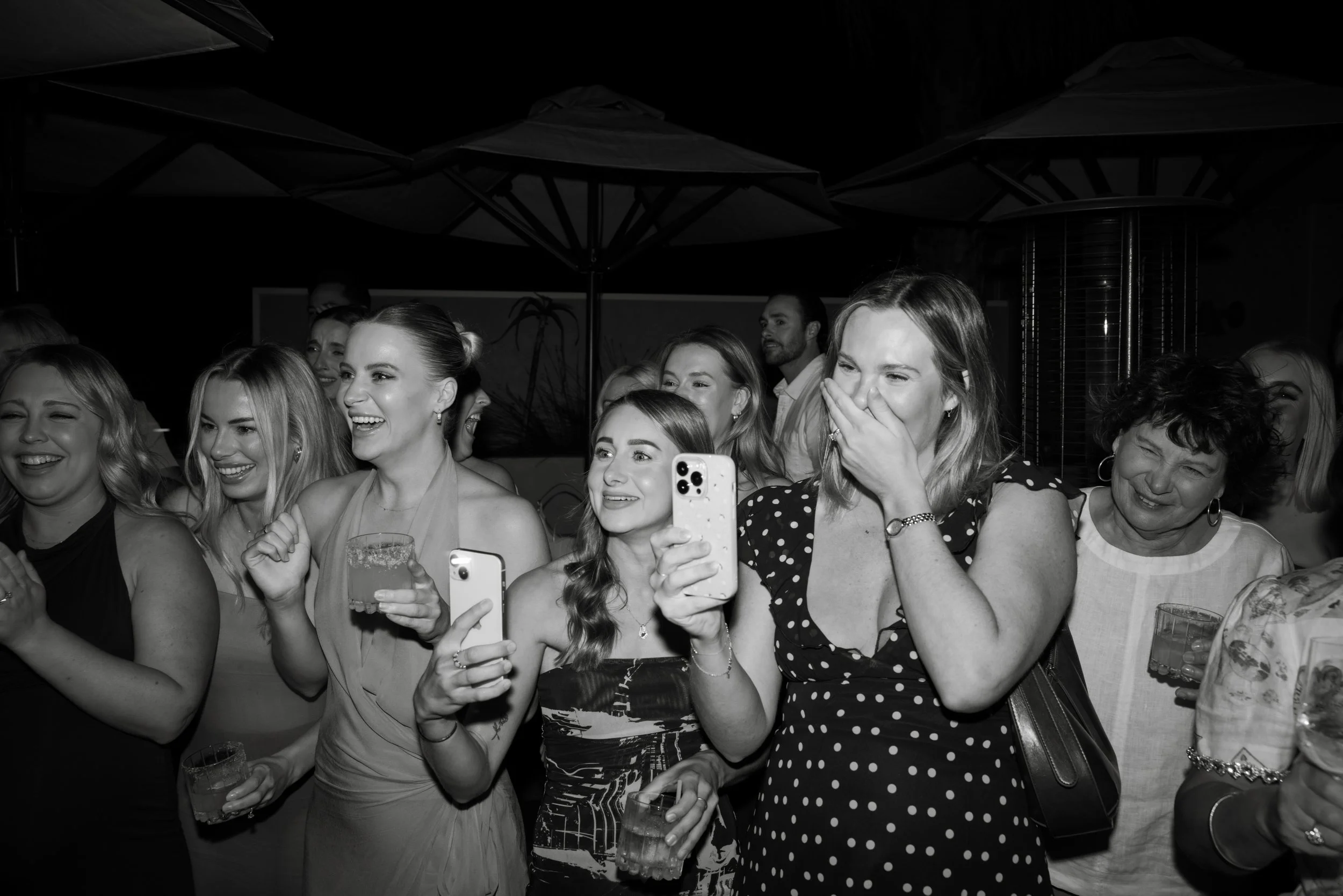 Group of women at a social event, some holding drinks, smiling, and taking photos. Event photography at Sueno in Nobby's - Gold Coast