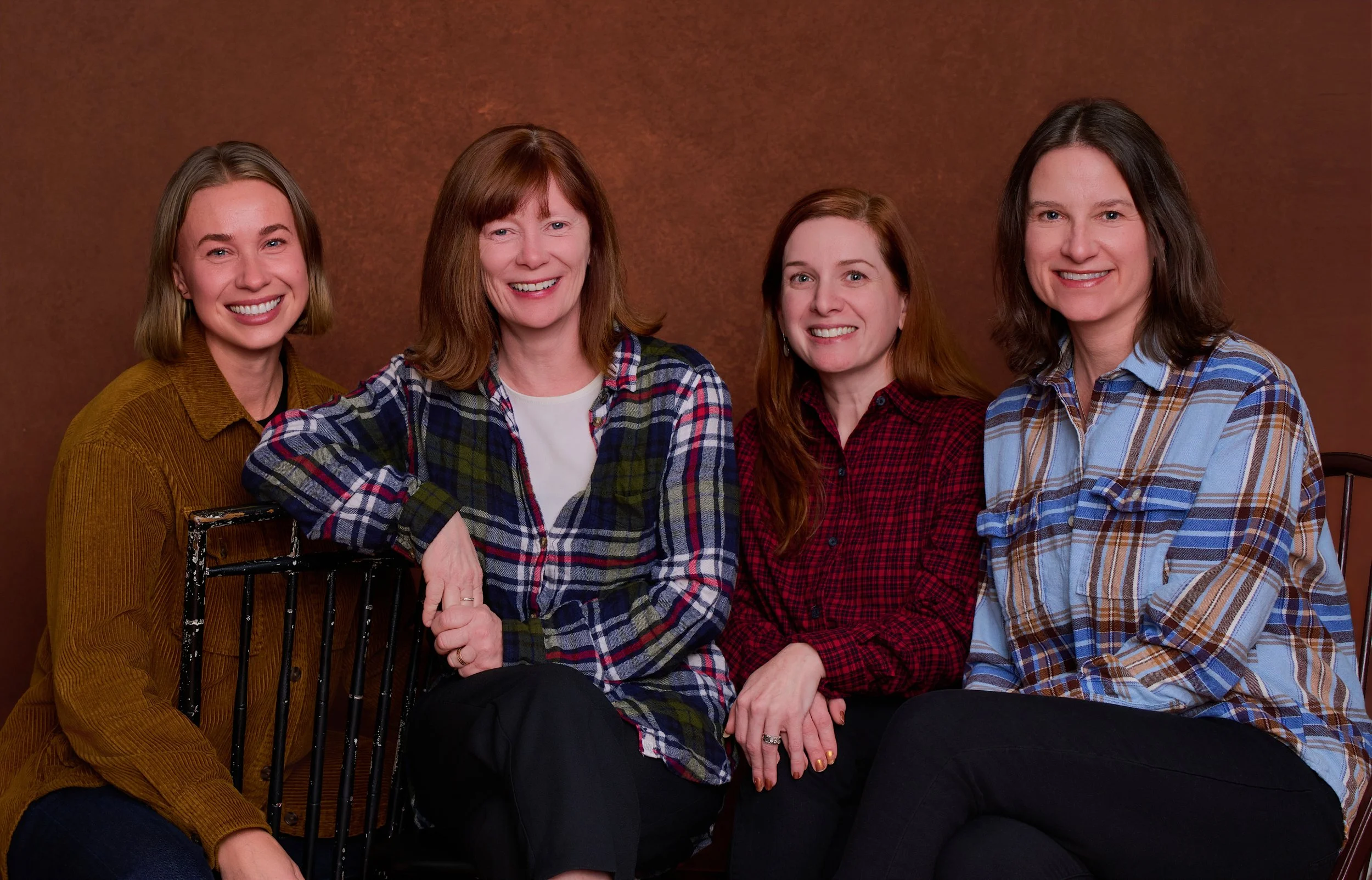 Four members of the Tandem Workforce Collaborative team — Brit, Donna, Melissa, and Abryana — smiling together in a casual group portrait against a warm rust-colored background.