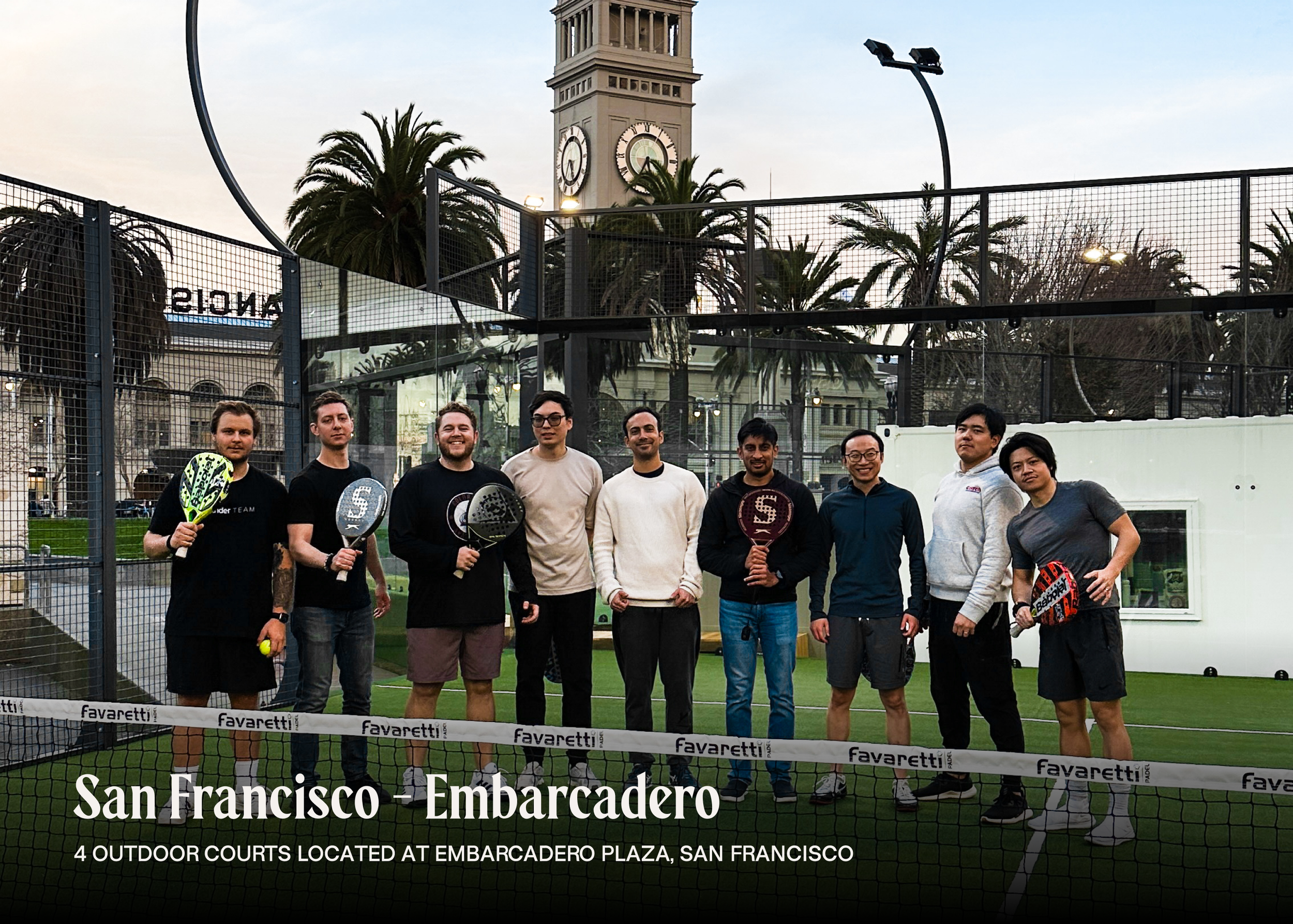 A group of ten people standing on an outdoor padel tennis court at sunset, holding rackets, with a cityscape and clock tower in the background, at Embarcadero Plaza, San Francisco.