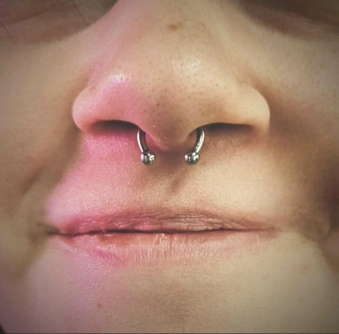Close-up of a person's nose with a septum piercing.