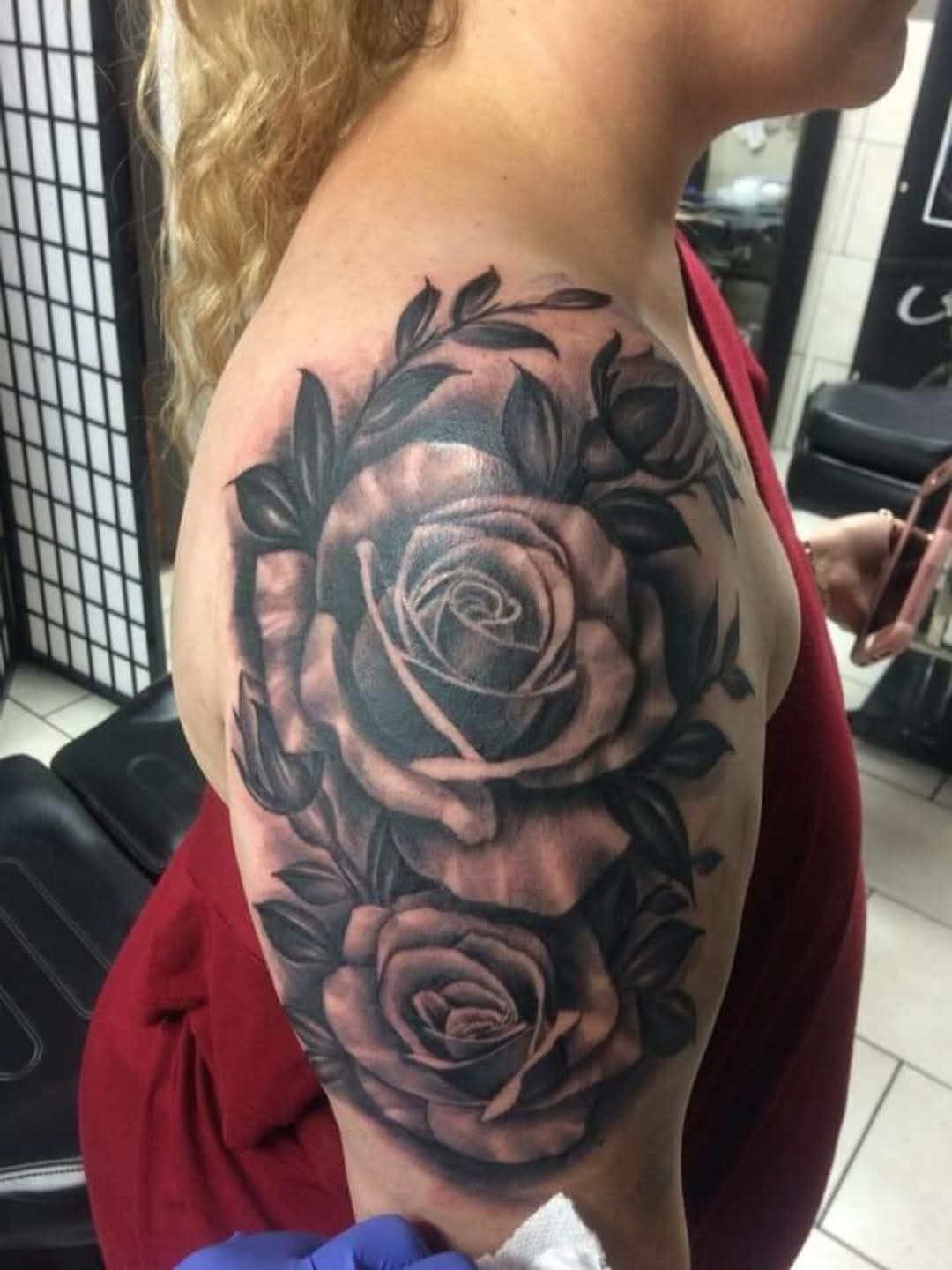 Black and gray rose tattoo on a woman's upper arm.