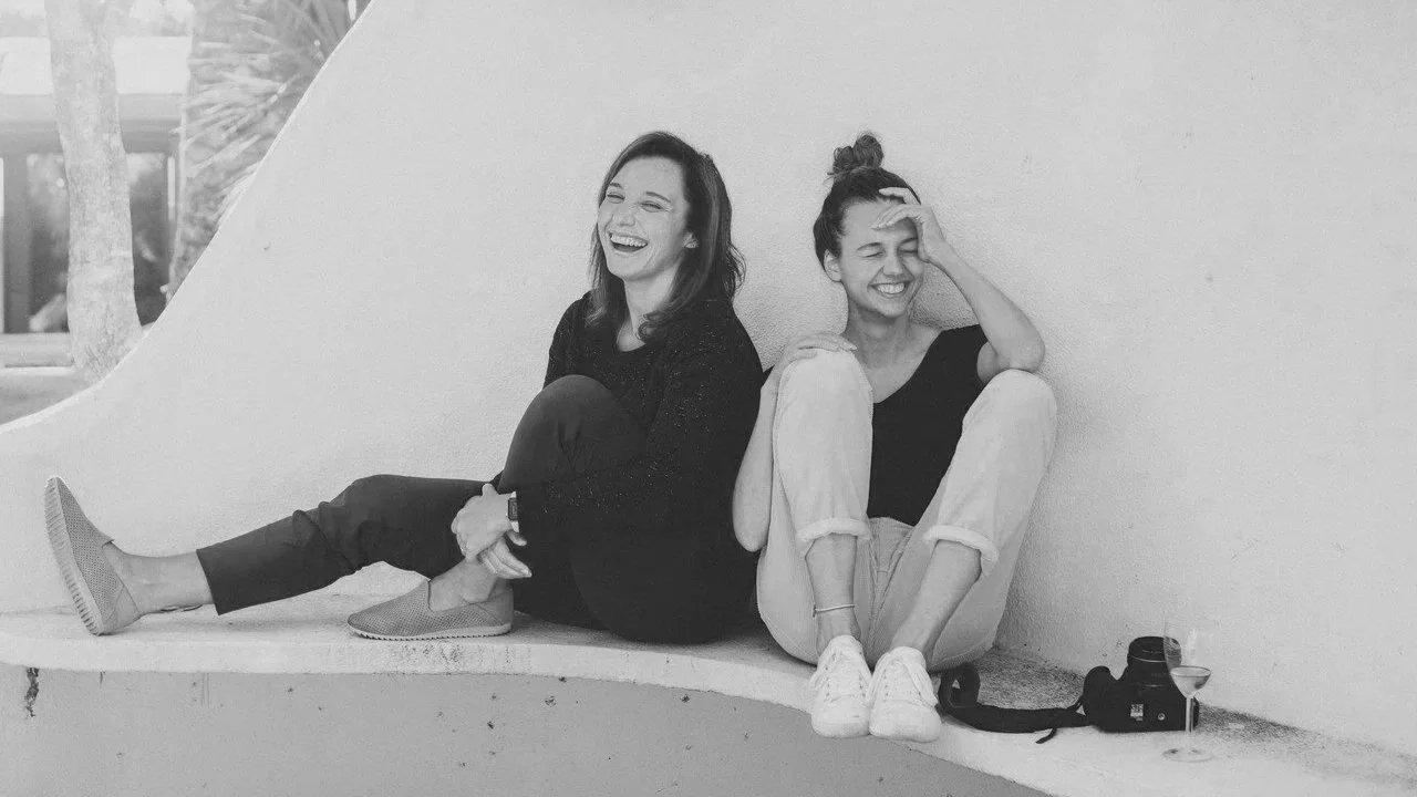 two women leaning against the wall laughing