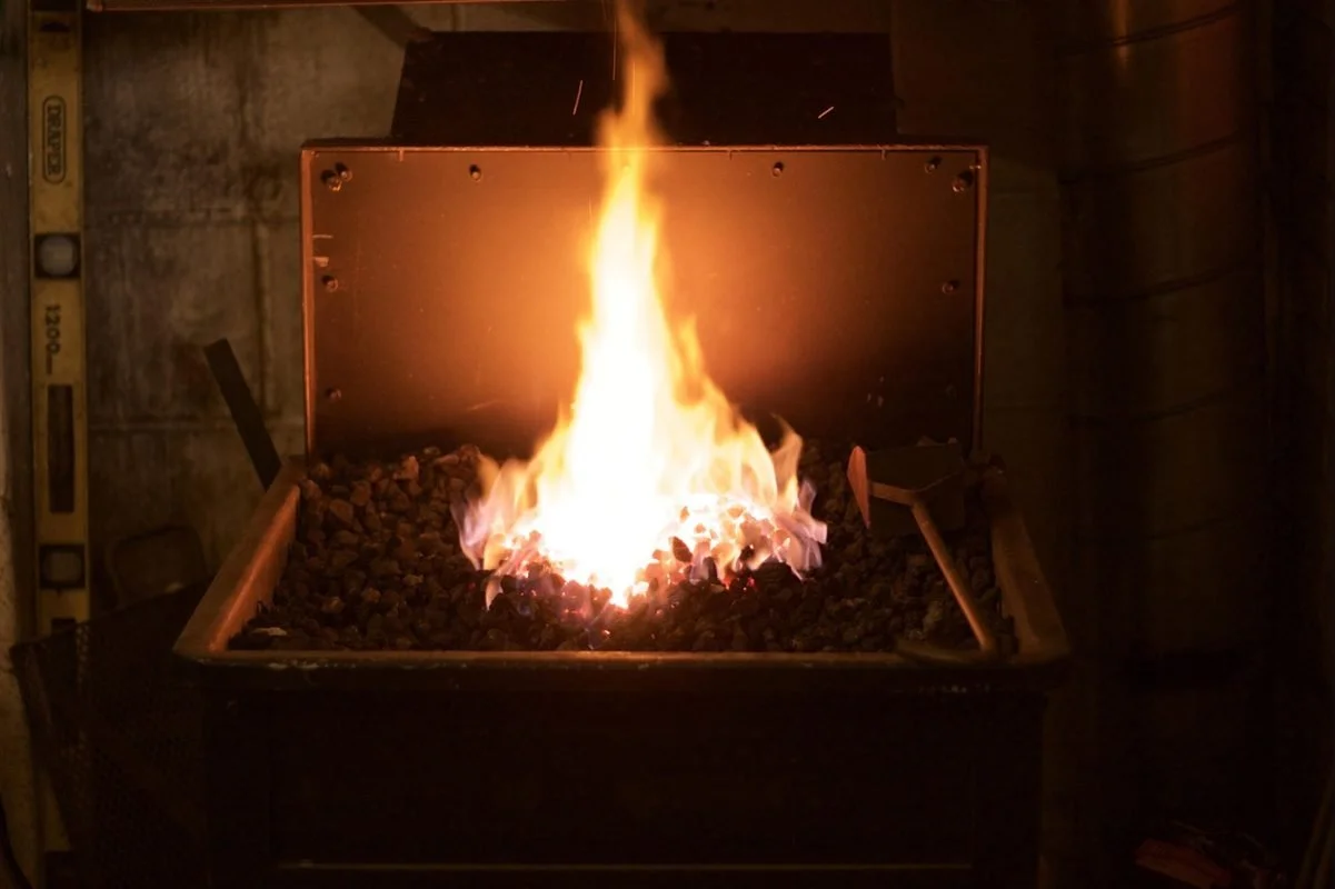 Blacksmith forging glowing iron, symbolizing therapy tempering a twice exceptional adult's overperformance