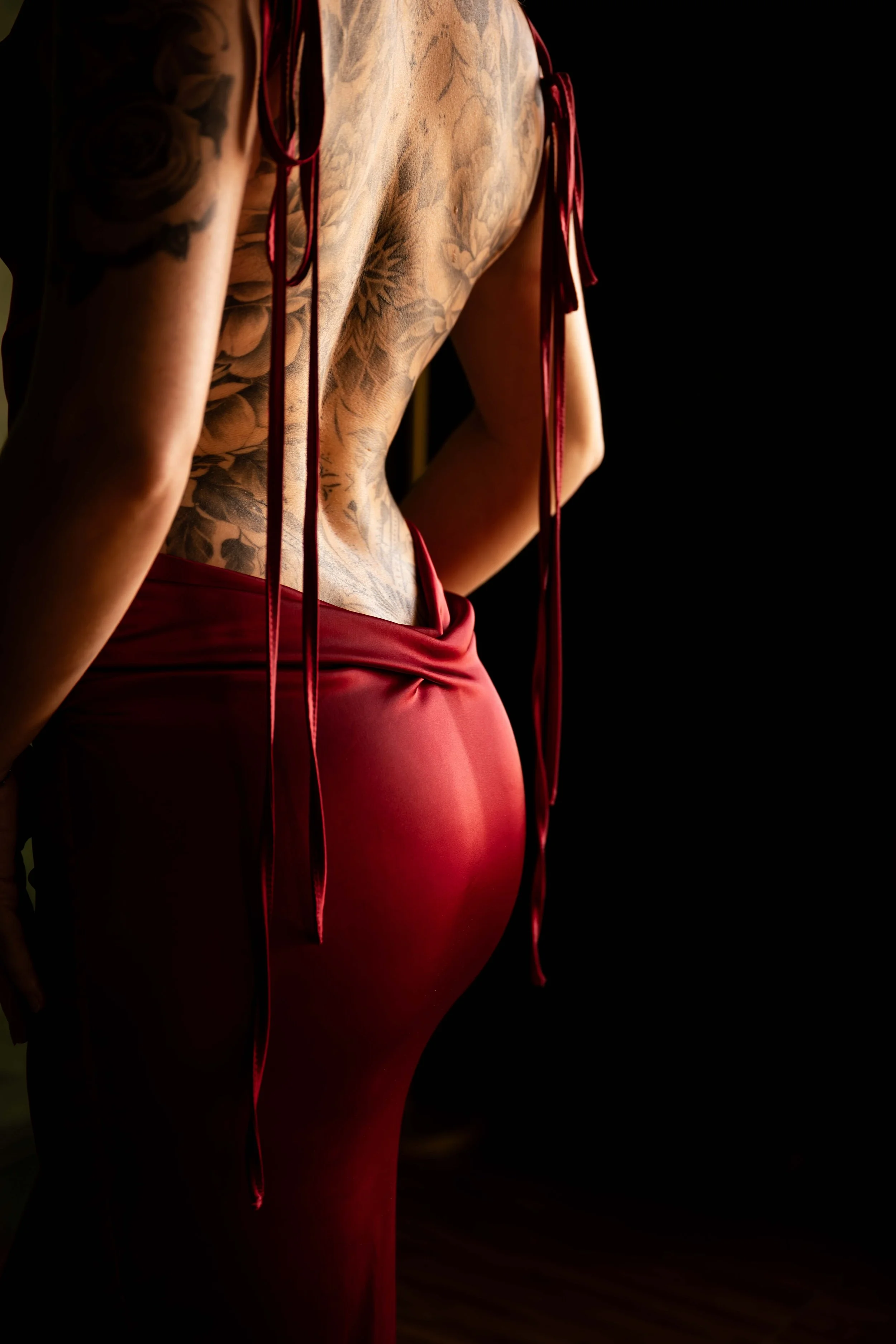 Close-up of a tattooed back draped in red satin during an artistic boudoir portrait