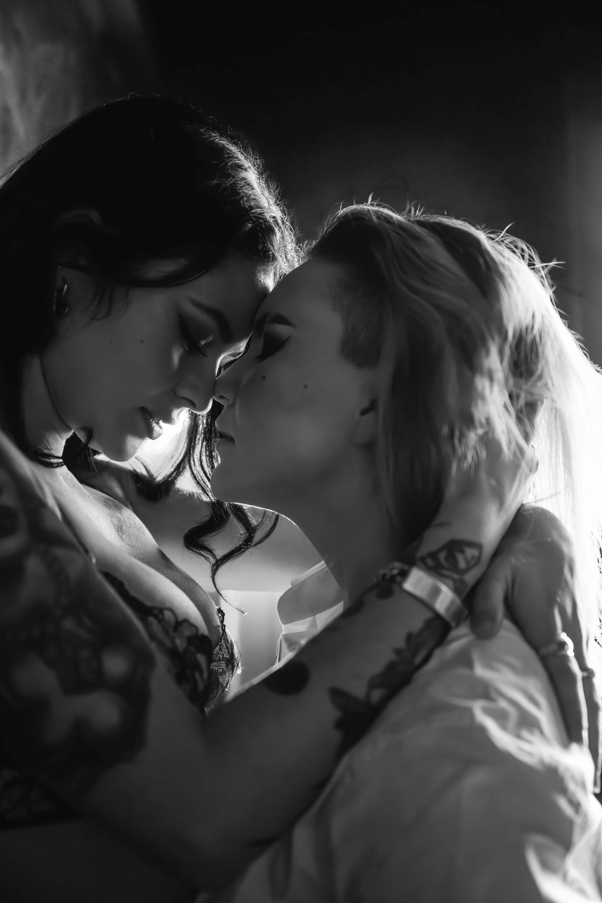 Two women touching foreheads during a romantic black-and-white couples boudoir session in Houston