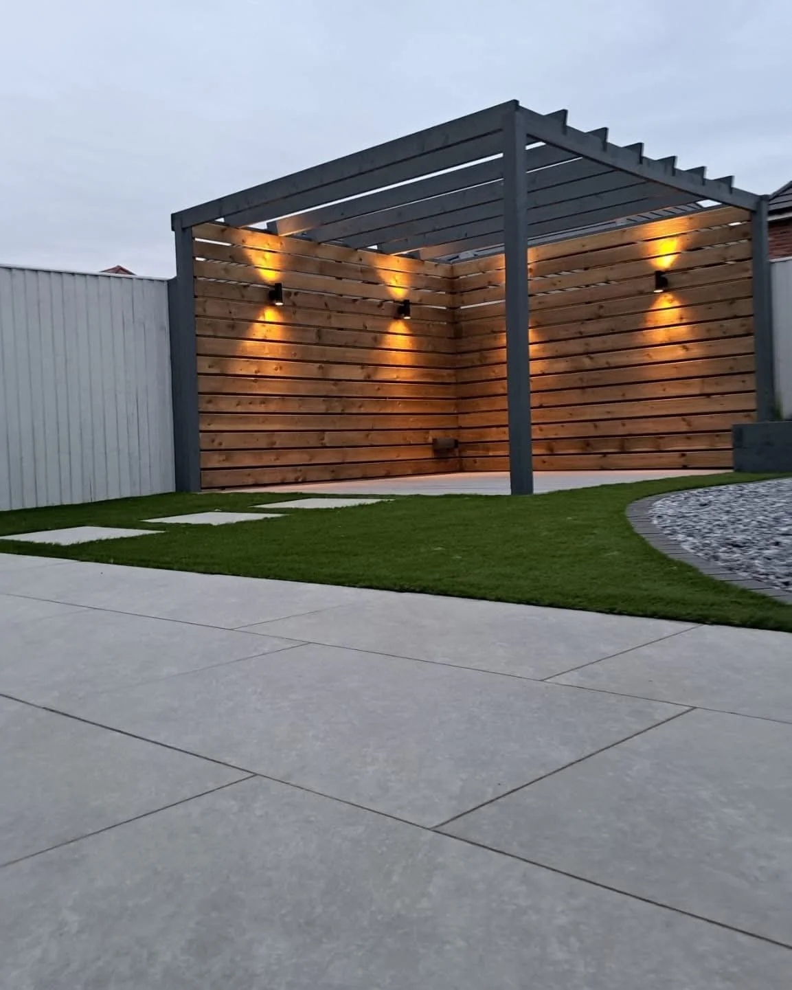Modern low maintenance garden design and build near Sandbach with porcelain paving installation, artificer grass, composite decking and bespoke pergola with garden lighting 