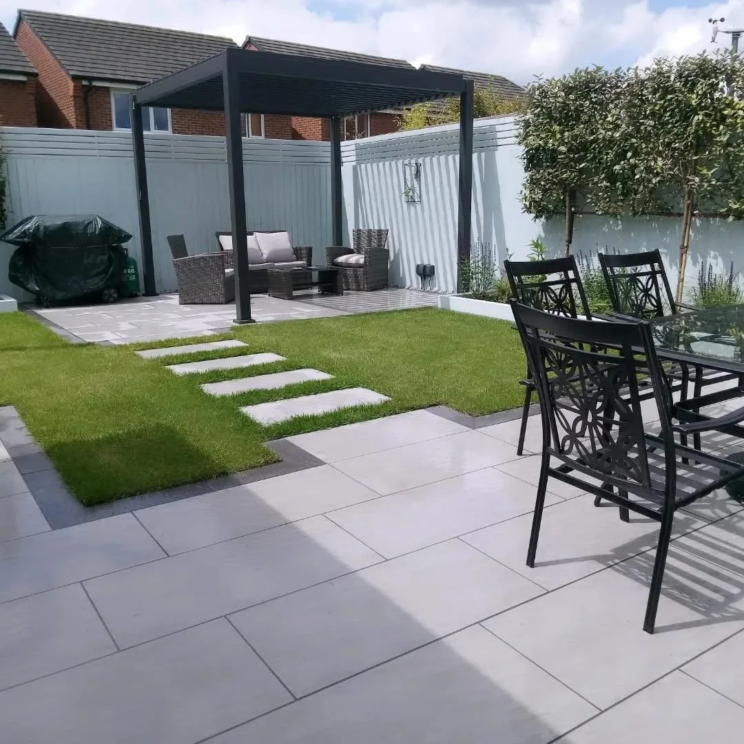 Modern low maintenance garden design and build in Moston, Sandbach with porcelain paving installation, new lawn turfing plus planting, lighting and pergola installation 