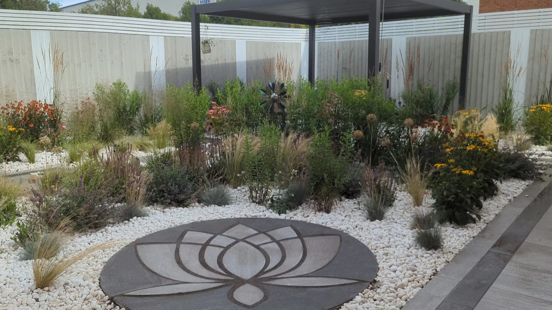 Porcelain paving designed and installed with prairie style gravel garden planting, composite decking, fencing and Pergola installation in Trentham