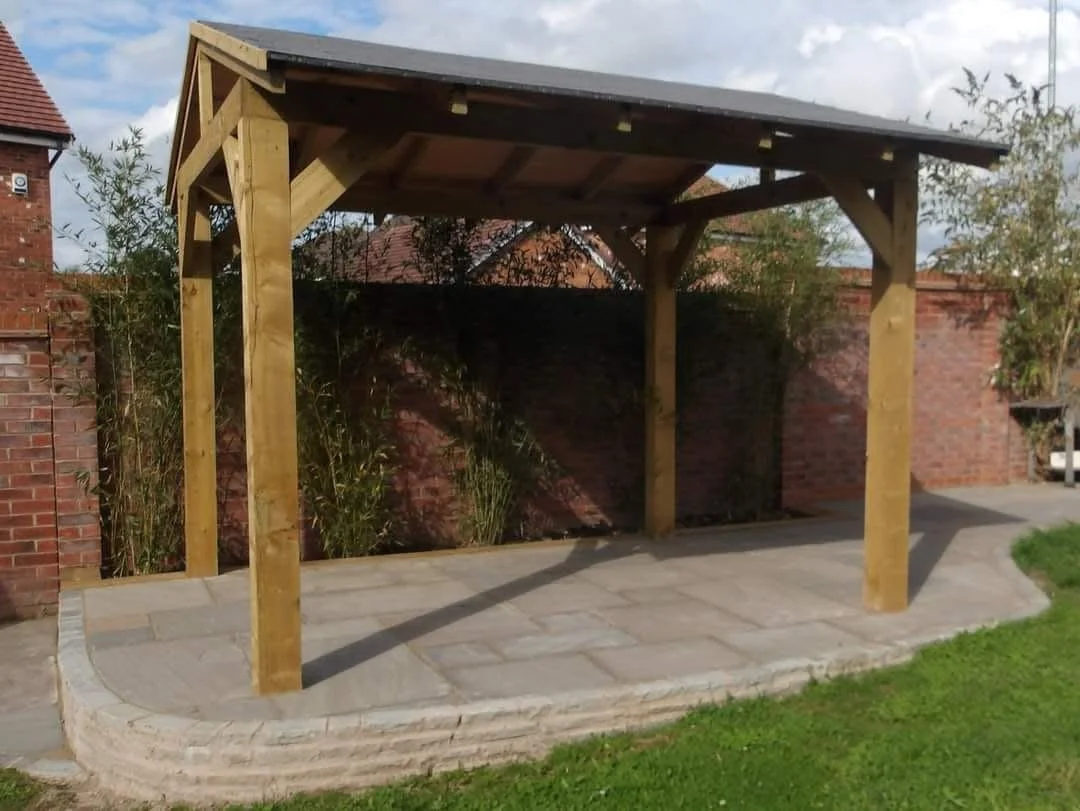 Raised indian sandstone patio installation with roofed pergola and walling in Sandbach 