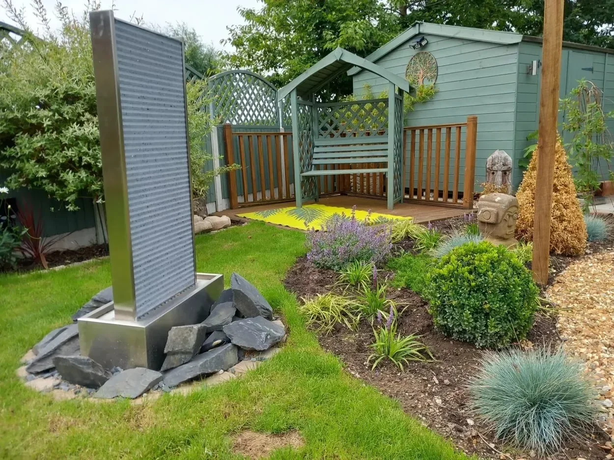 Freestanding water feature with decking and planting installed by Goodwin Gardens Ltd in Haslington, Crewe