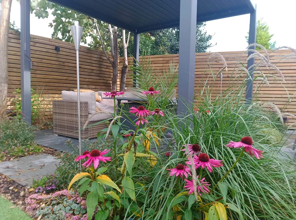 Flowers looking beautiful in front of a relaxing outdoor area with deck and pergola installed by Goodwin Gardens Ltd in Elworth, Sandbach.