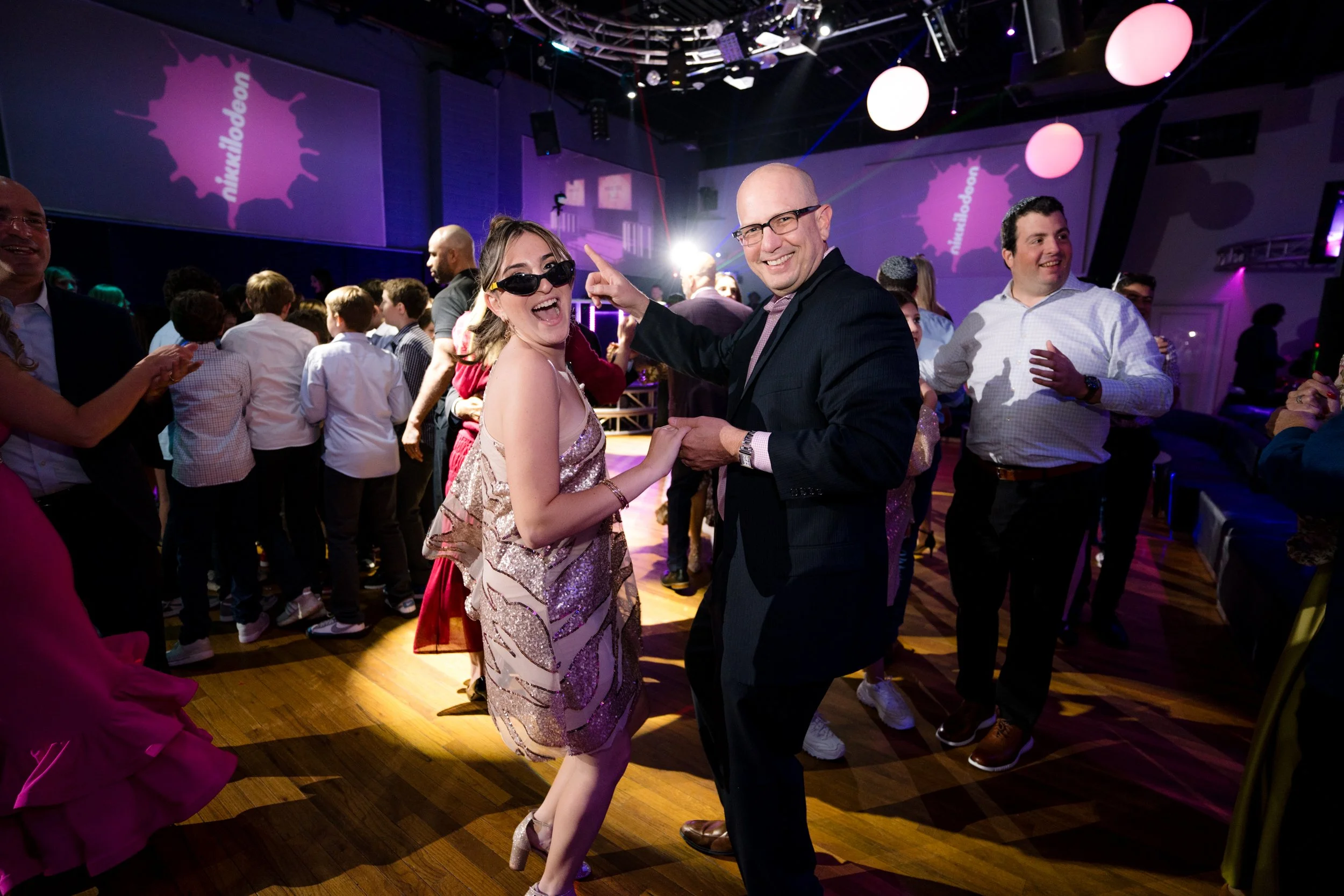 People dancing and celebrating at a party with colorful lighting.