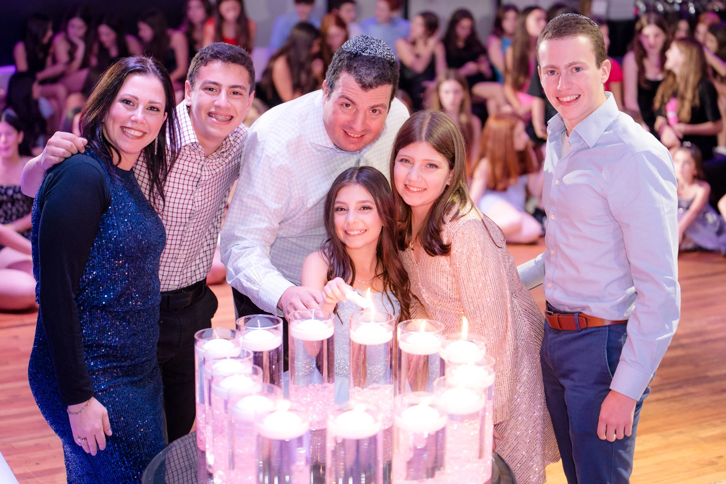 Group of people smiling around a candle-lit table at an event.