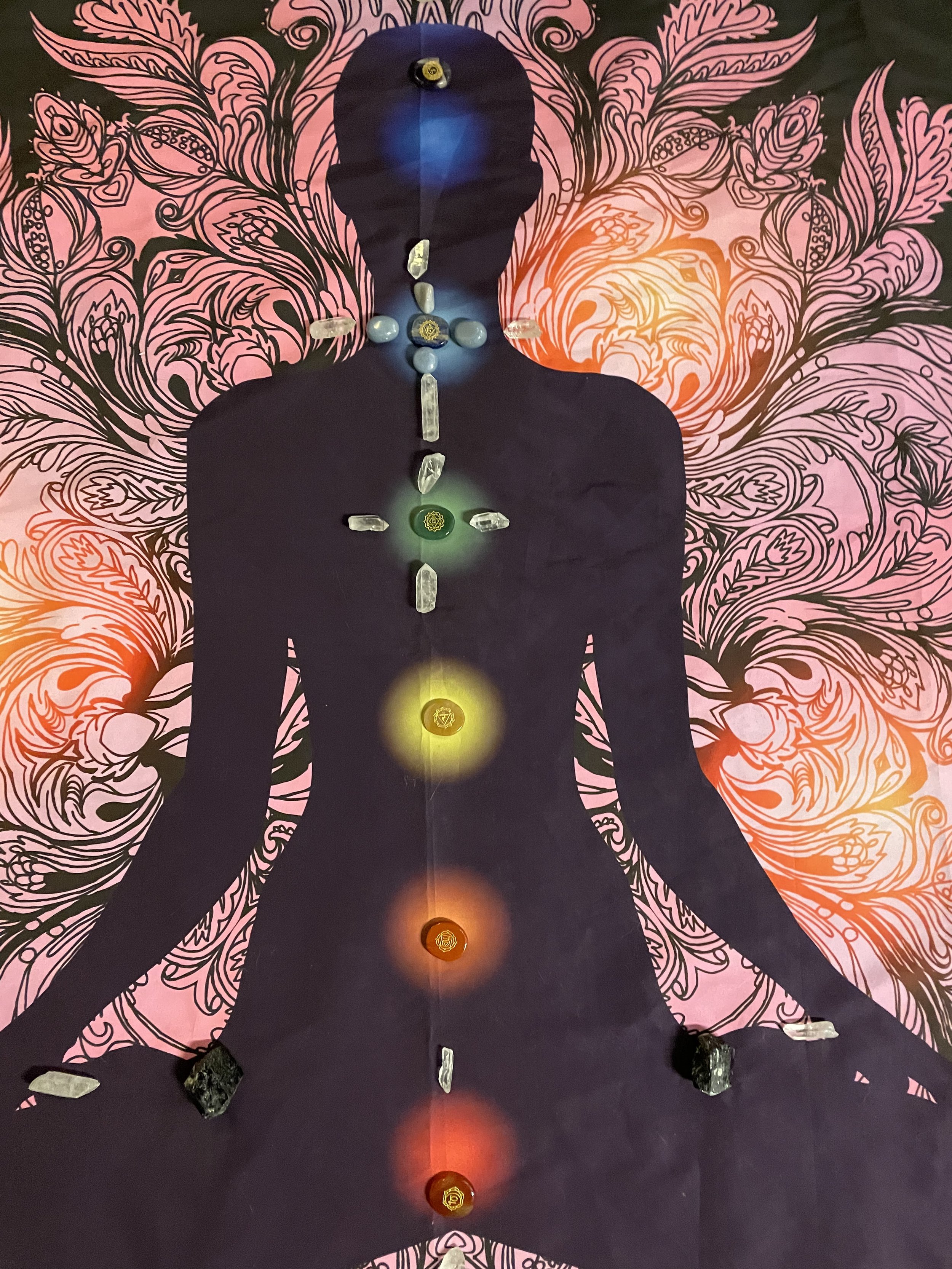 Silhouette meditation with chakra stones and crystals on colorful patterned background.