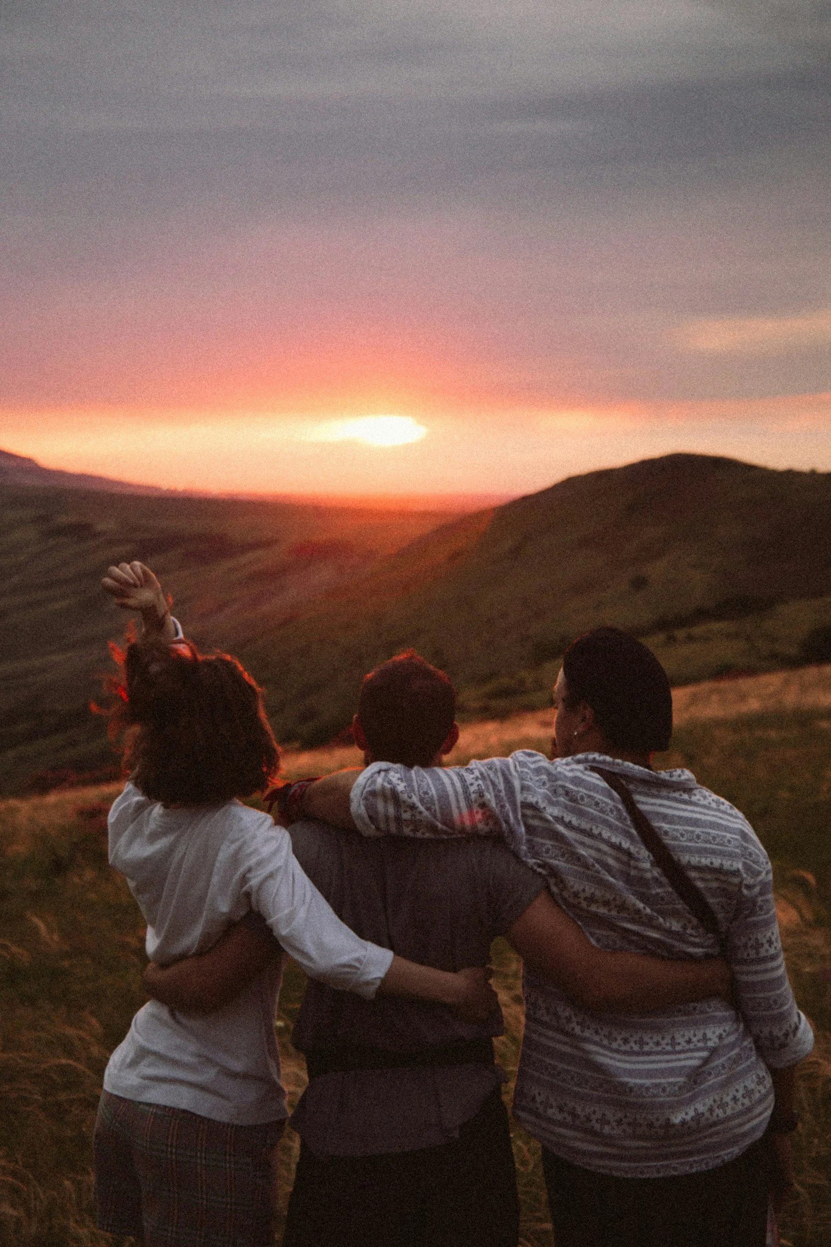 Three people watching a sunset