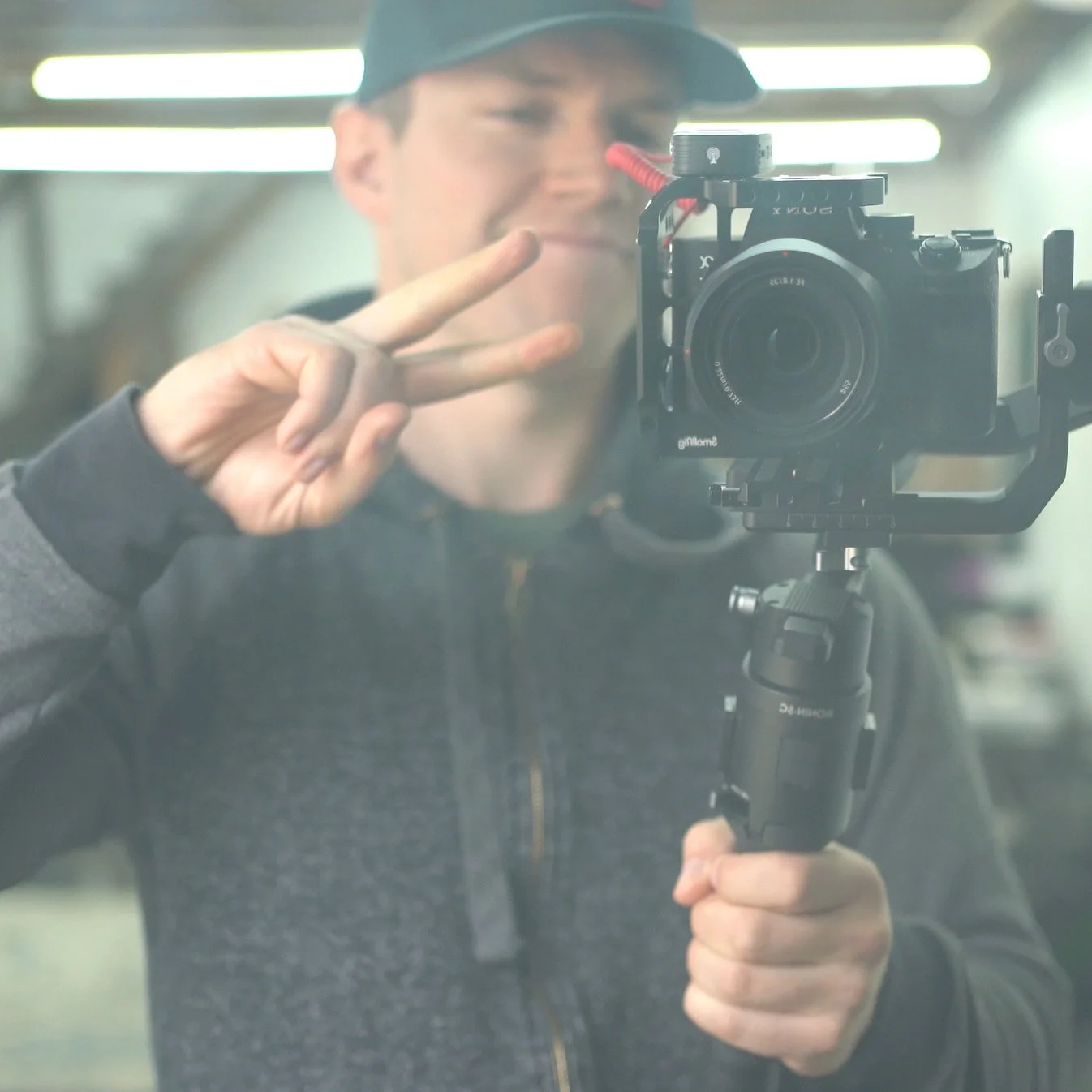 A person taking a selfie in front of a camera mirror, making a peace sign with their right hand.
