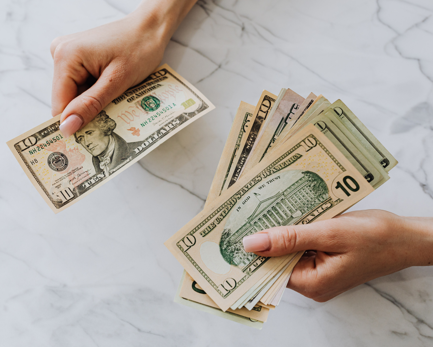 Hands separating stacks of cash