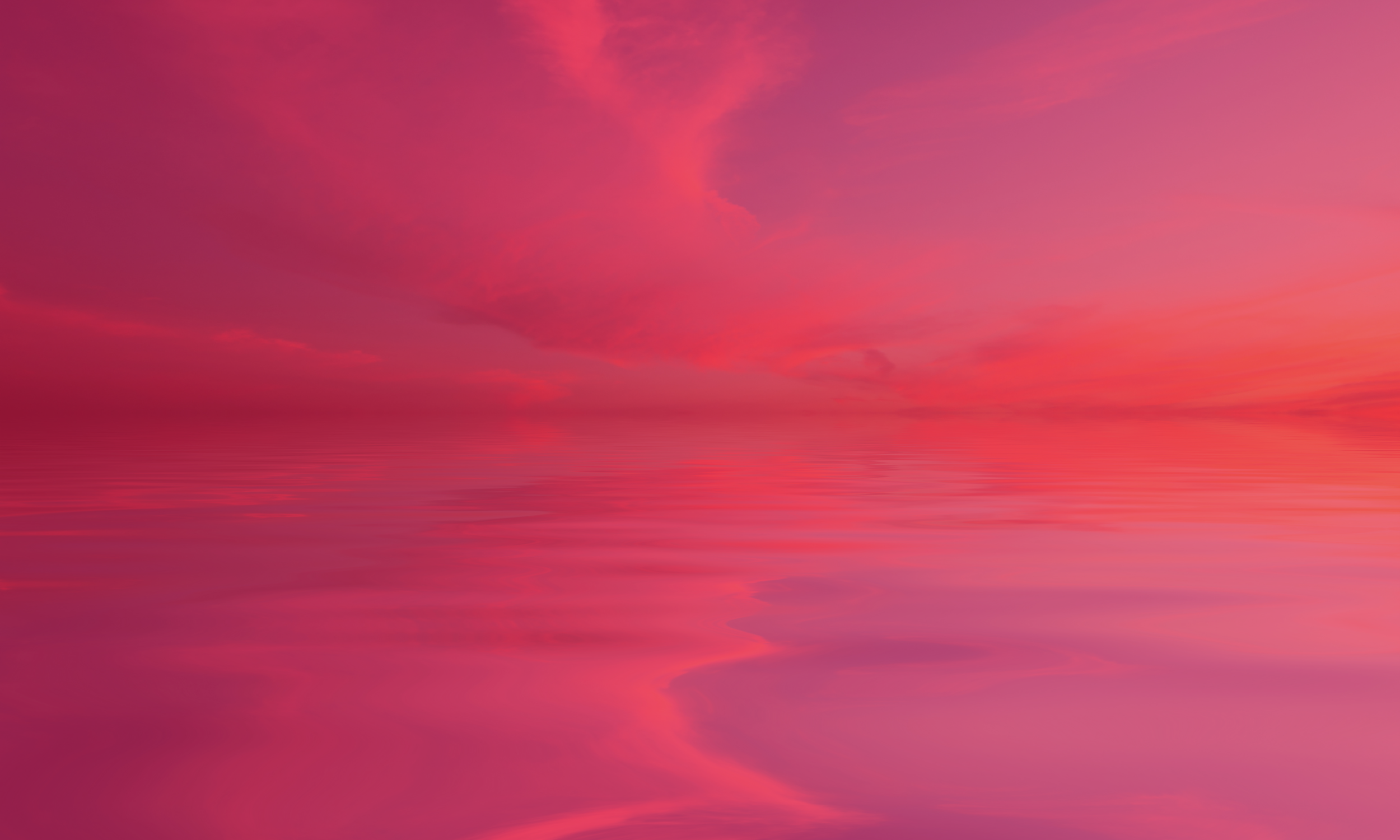 Pink and purple sunset over a calm body of water with soft clouds in the sky.