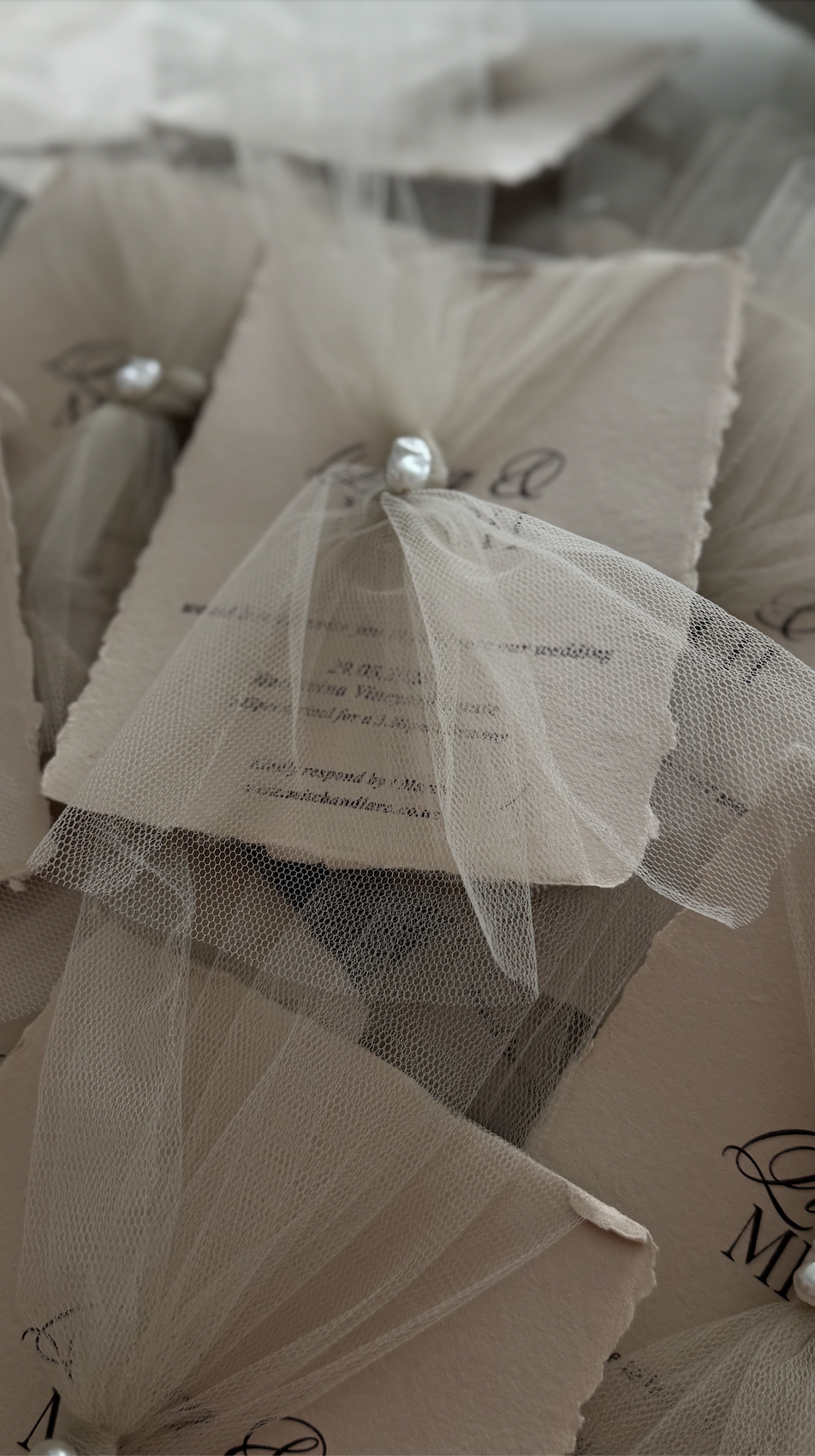 Custom handpaper stone deckled edge invitation with tulle fabric and pearl detail