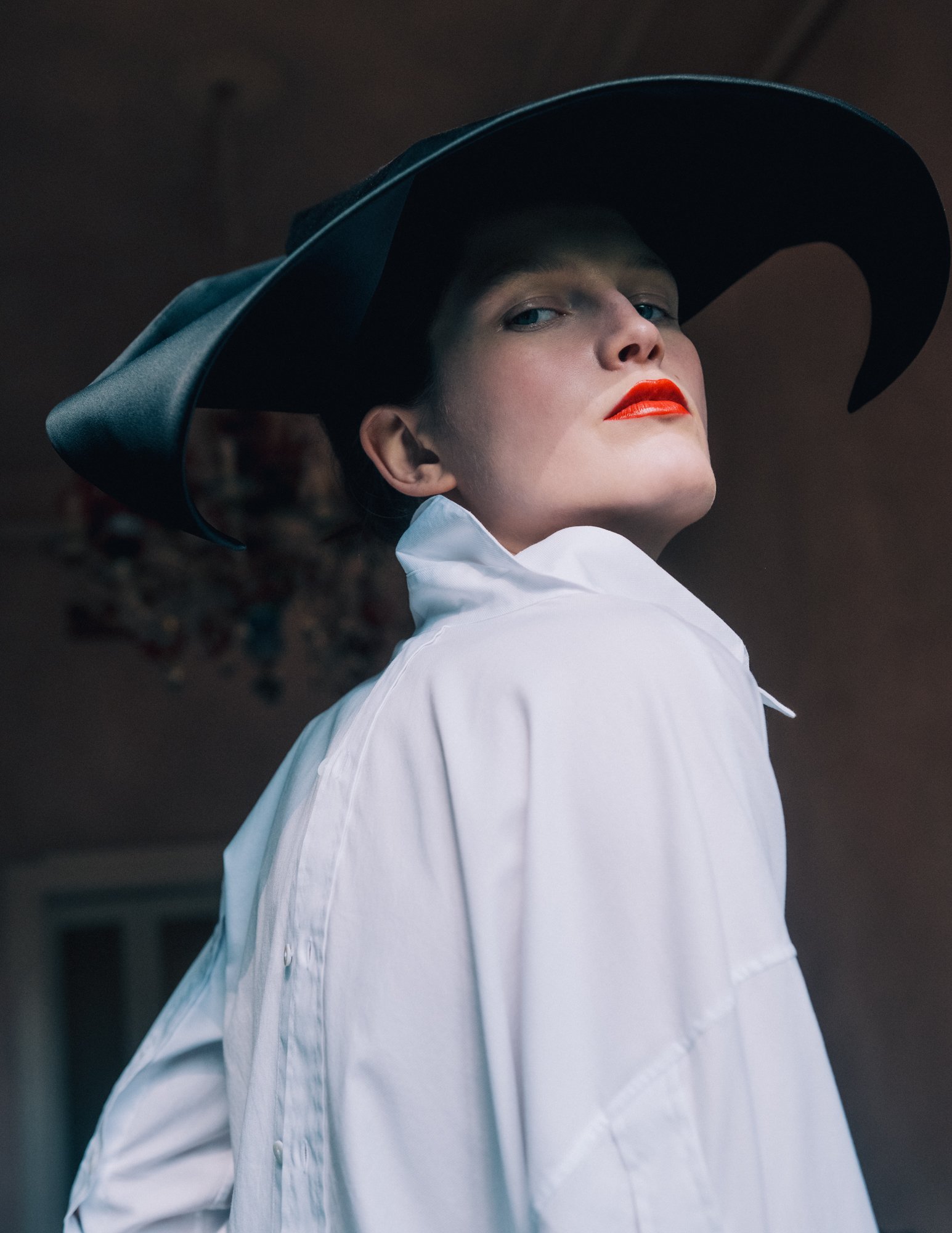 A person dressed as the Wicked Witch of the West from The Wizard of Oz, wearing a black pointed hat, white shirt, and red lipstick.