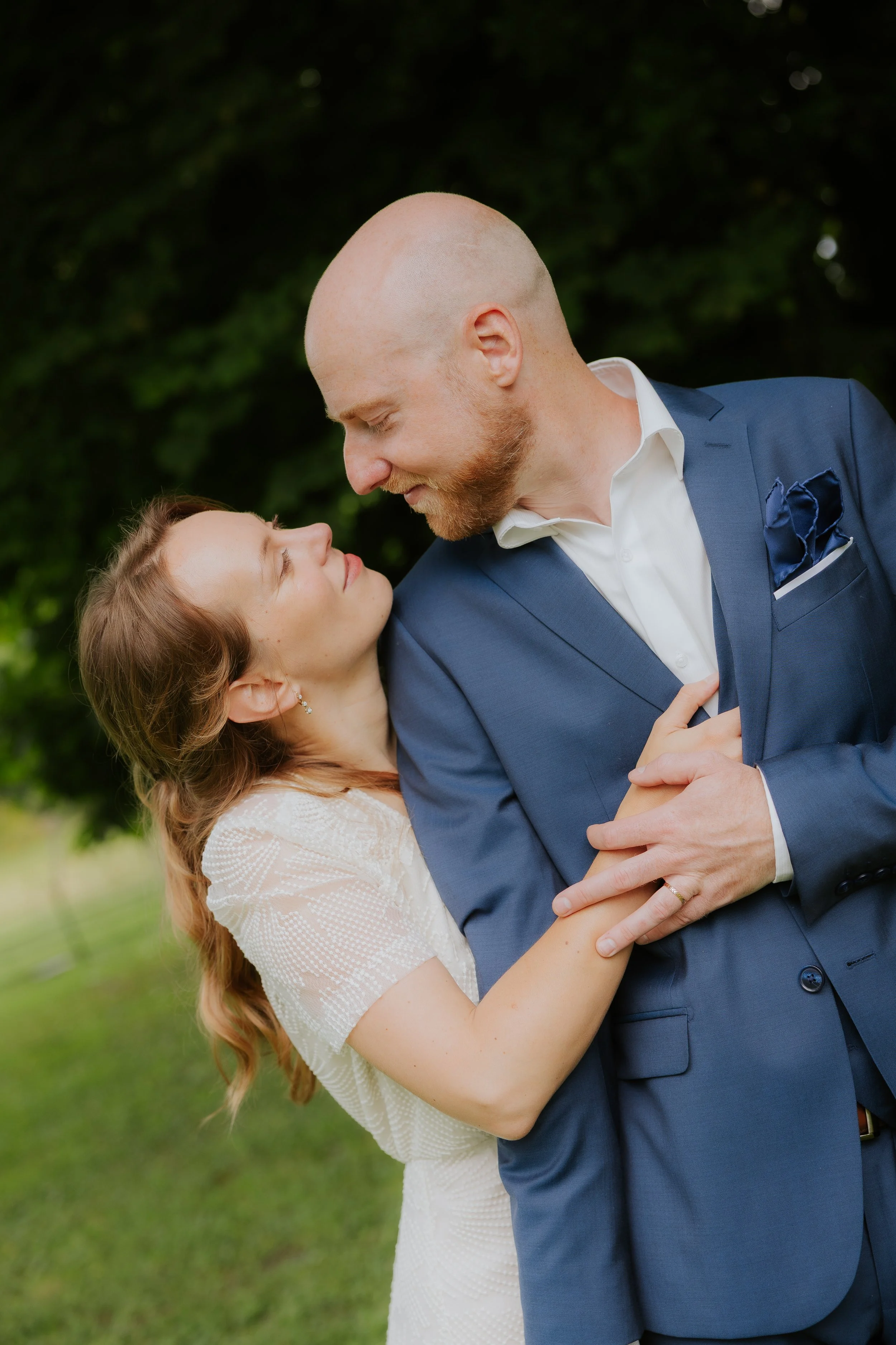 Un couple dans une ambiance romantique, la femme regarde l'homme dans les yeux, tout en étant près d'une nature verdoyante.