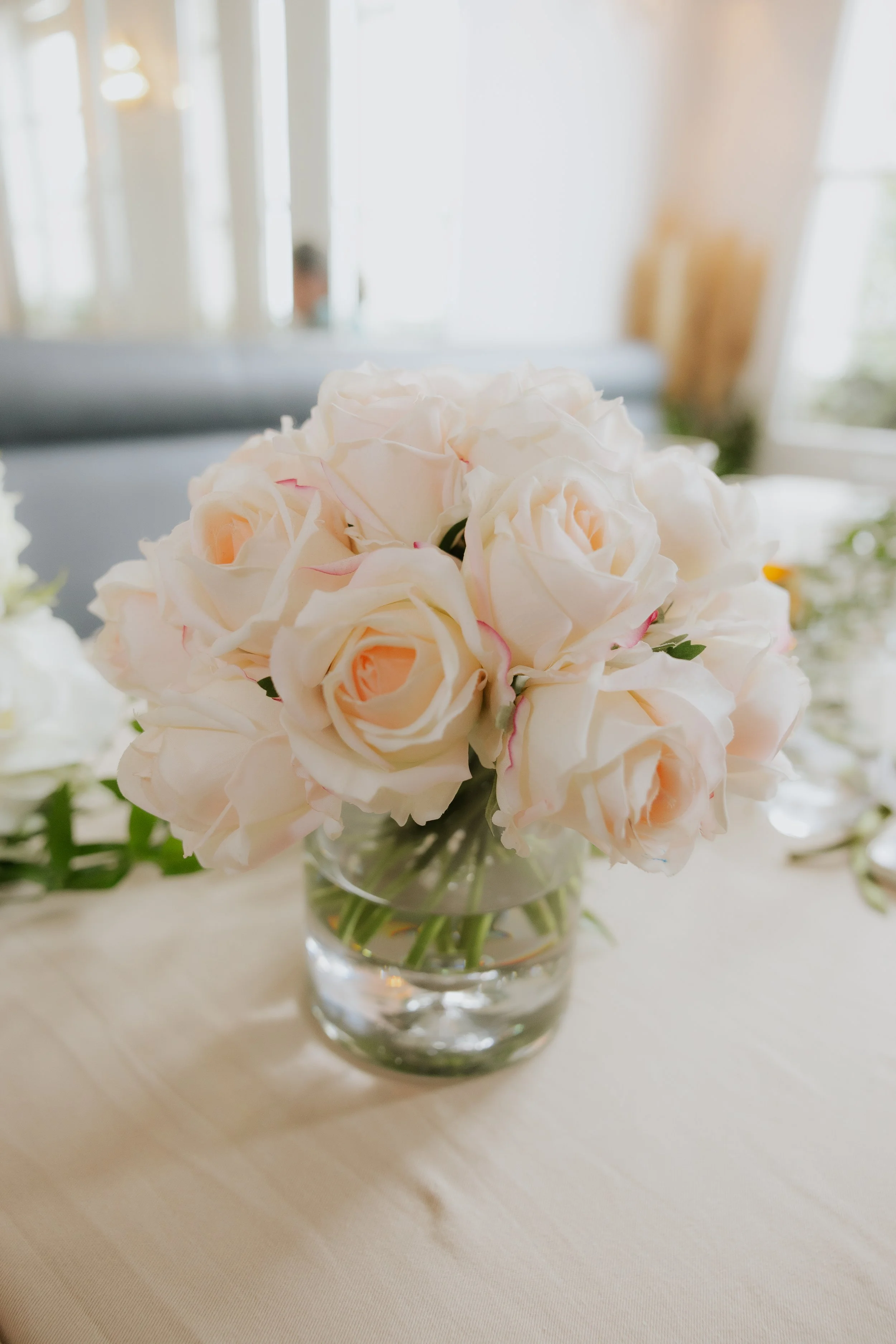 Bouquet de roses blanches dans un vase en verre sur une table.