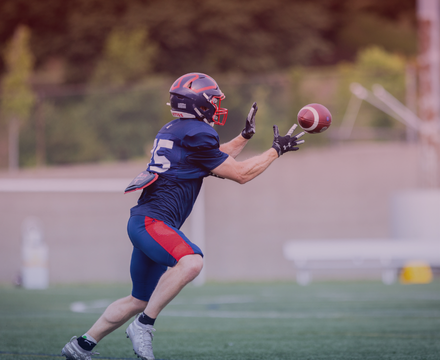 Football player reaching out to catch a football on a field