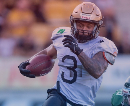 American football player in uniform running with a football during a game.