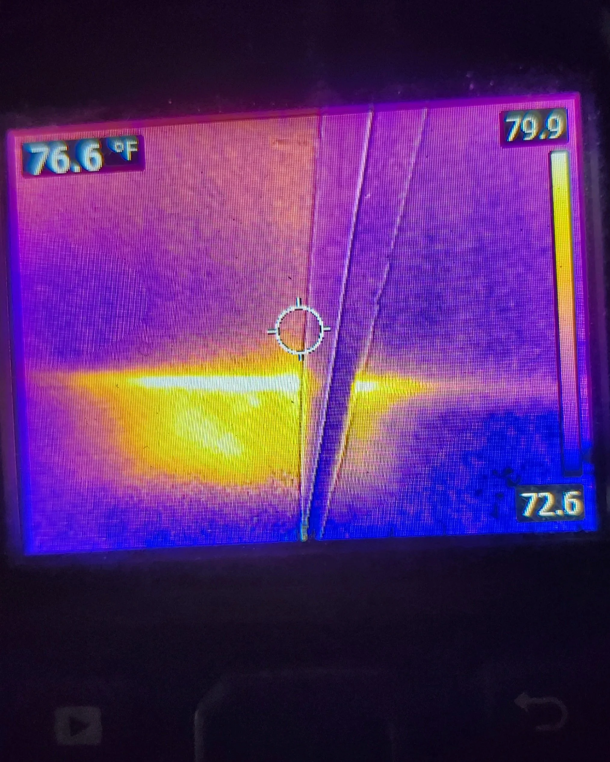 Colorful thermal imaging screen displaying two temperature readings, 76.6°F on the left and 79.9°F on the right, with a circular crosshair in the center.