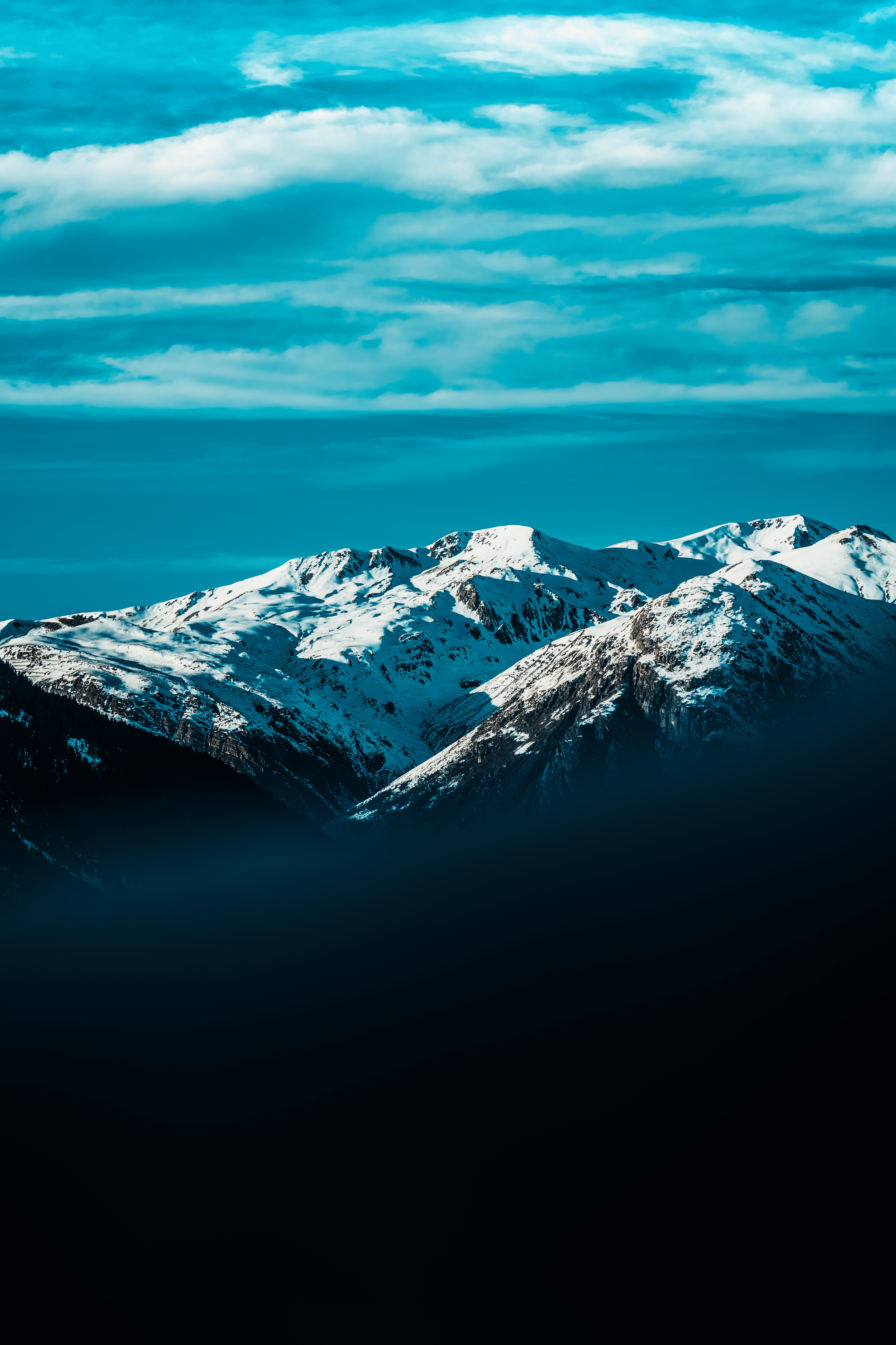 Montañas cubiertas de nieve bajo un cielo con nubes blancas y azules.