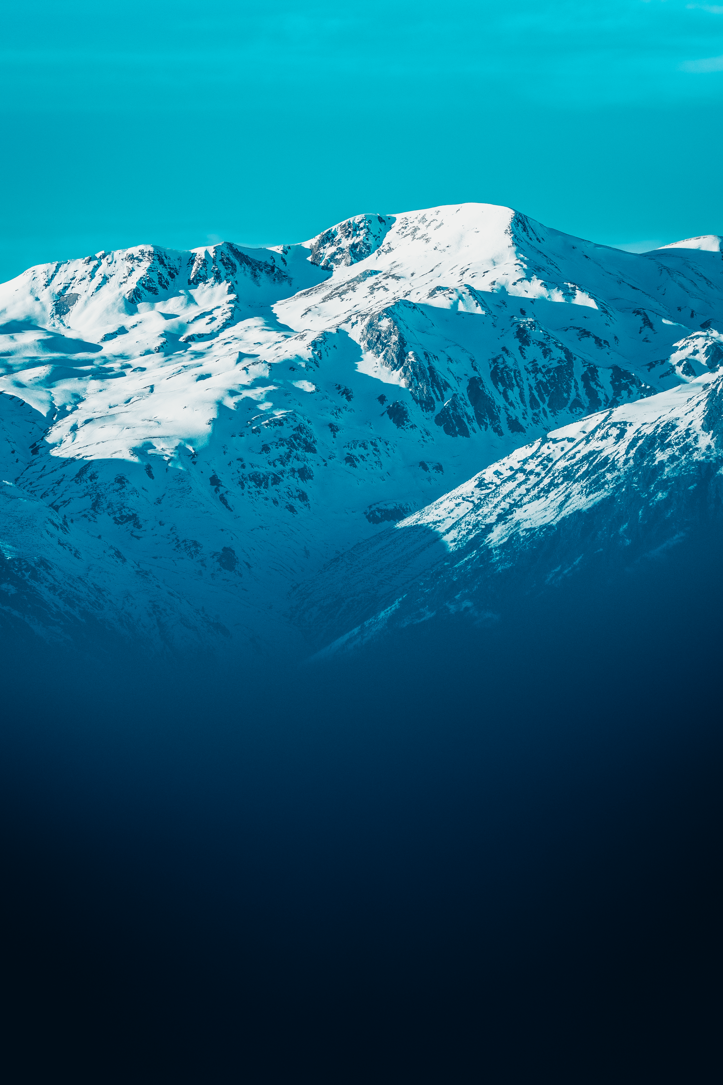 Montañas nevadas bajo un cielo azul vívido.