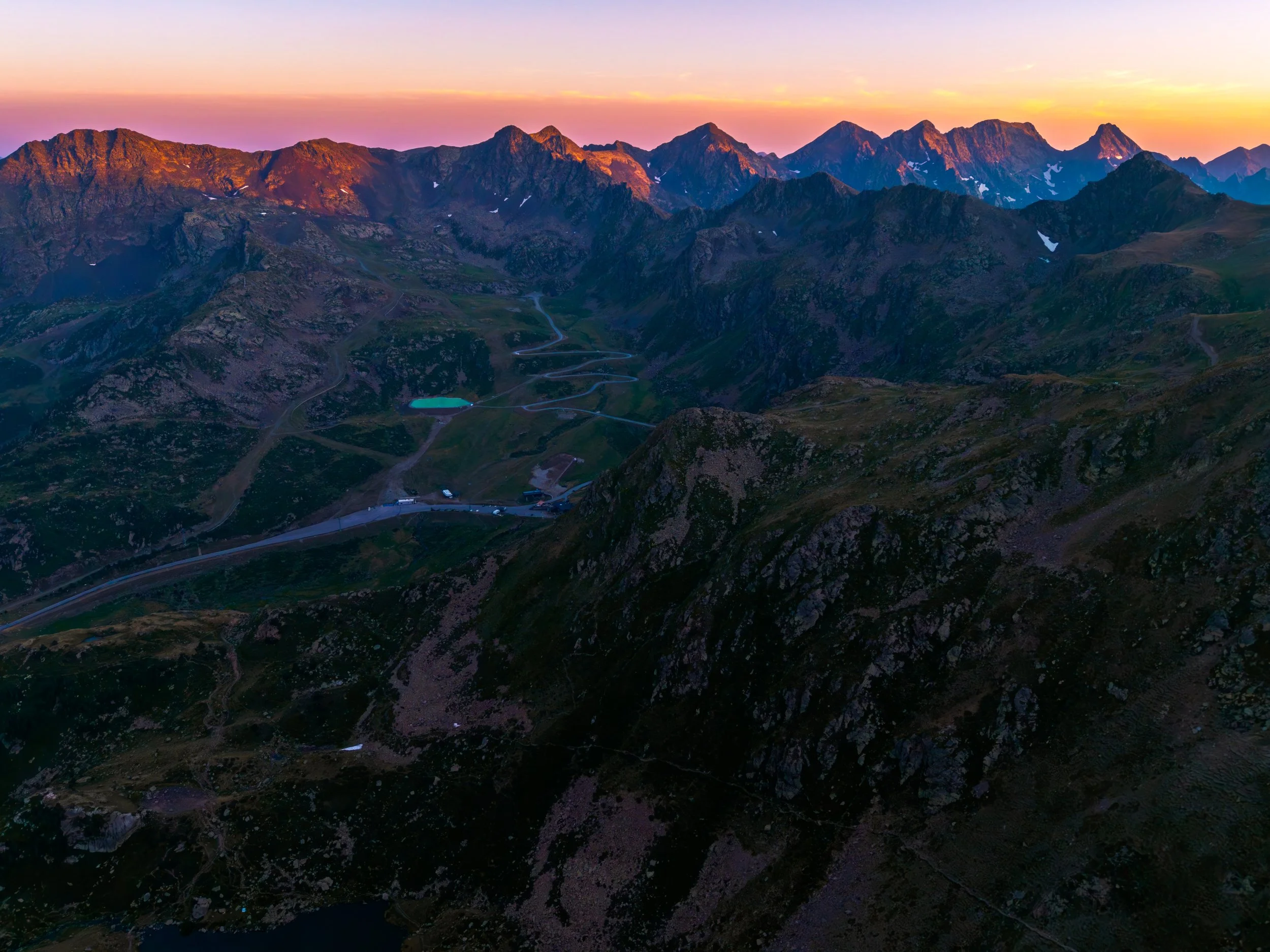 Un paisaje de montañas con picos rocosos al atardecer, cielo en tonos pastel.