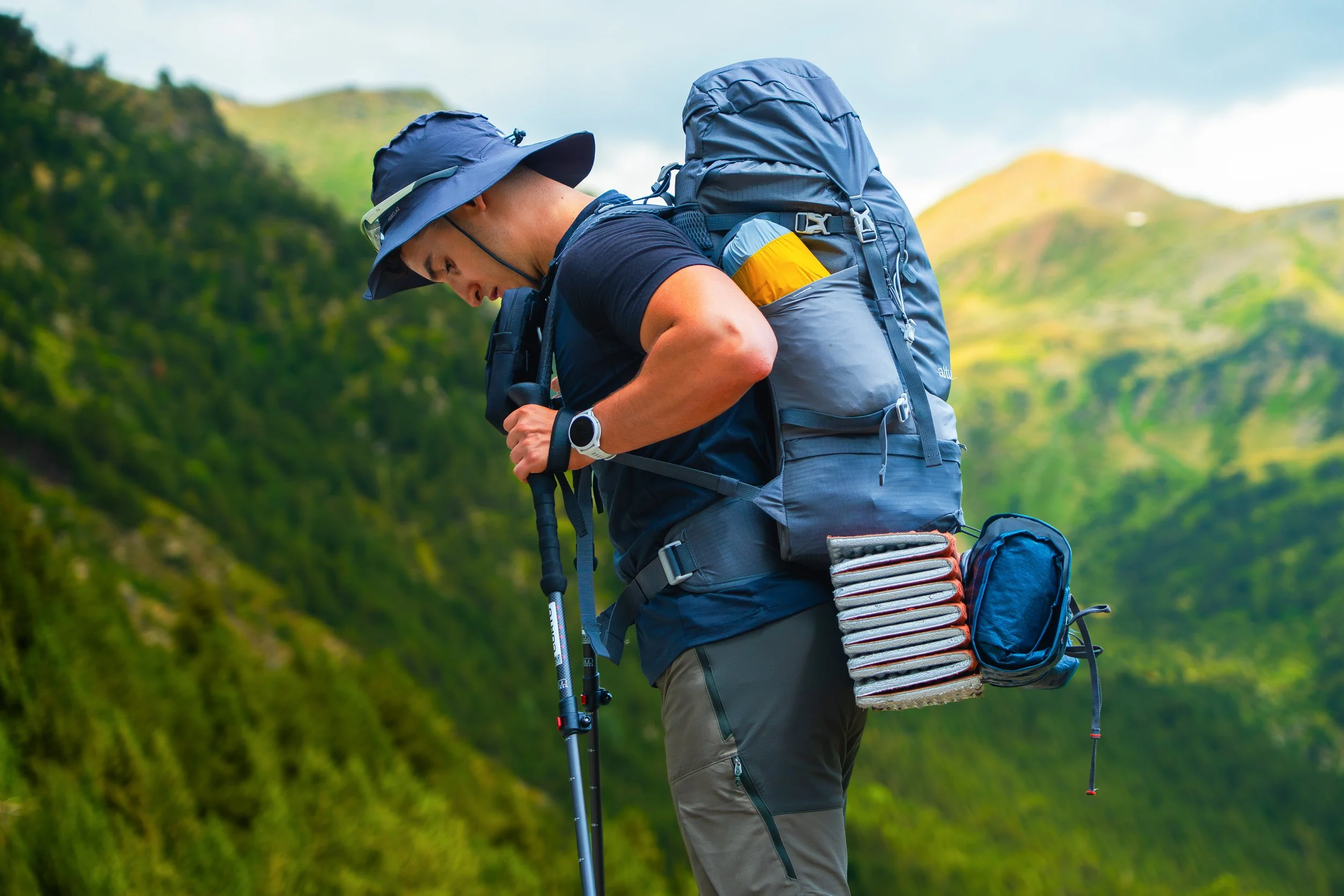 Persona haciendo senderismo en una zona montañosa con mochila y equipo de camping.