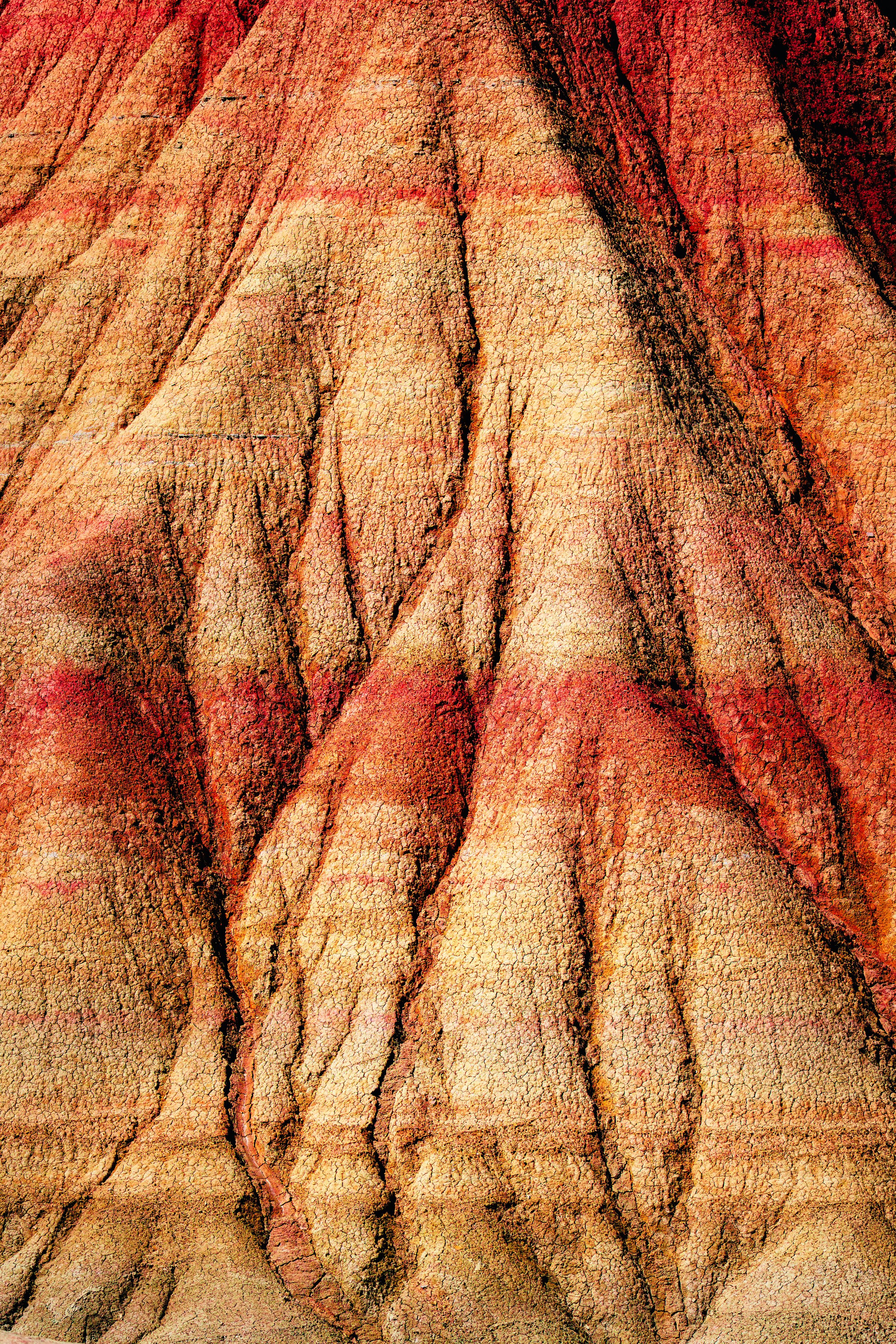 Textura de tierra reseca con grietas y tonos rojizos y marrón.