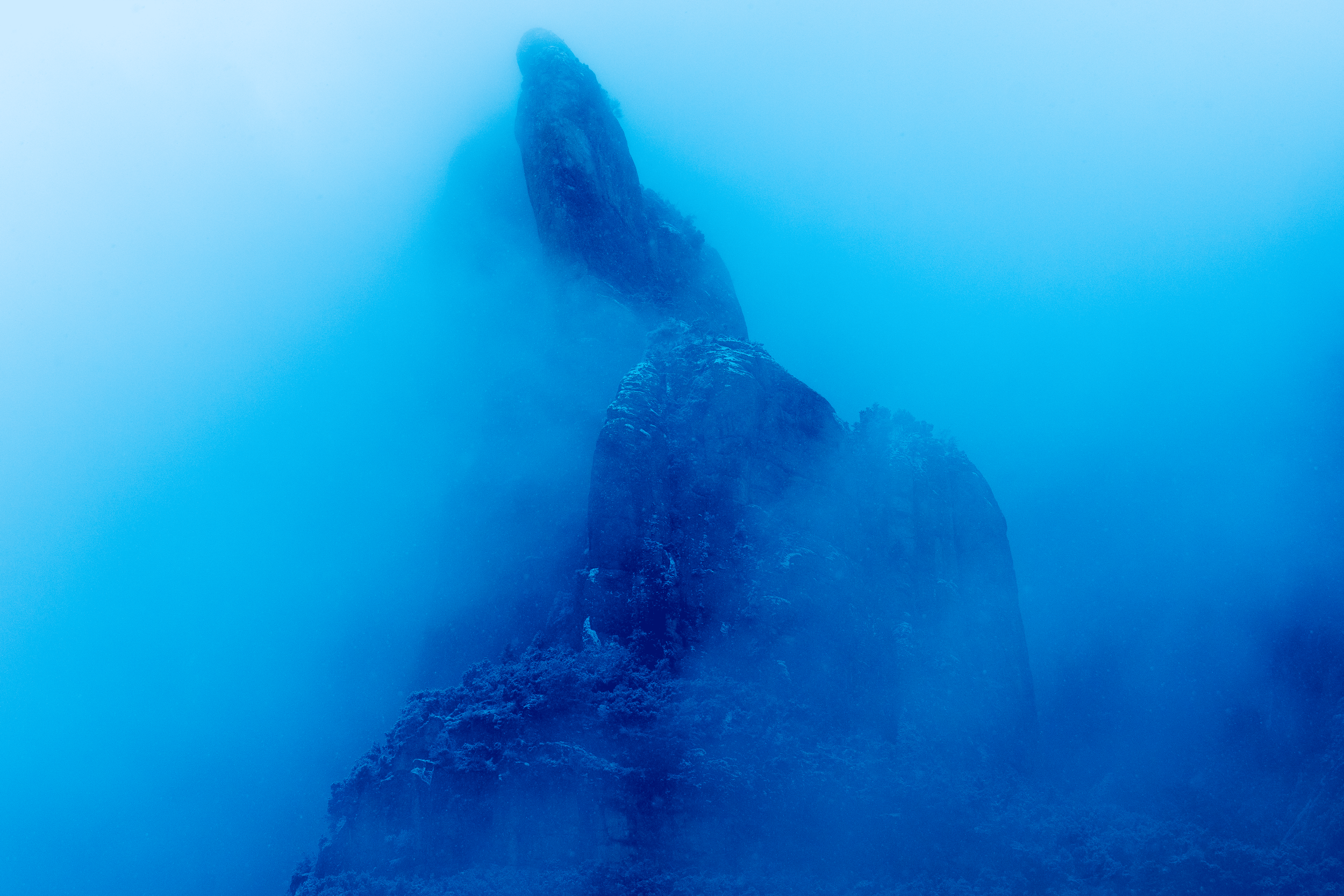 Formaciones rocosas en una montaña envuelta en niebla azul.