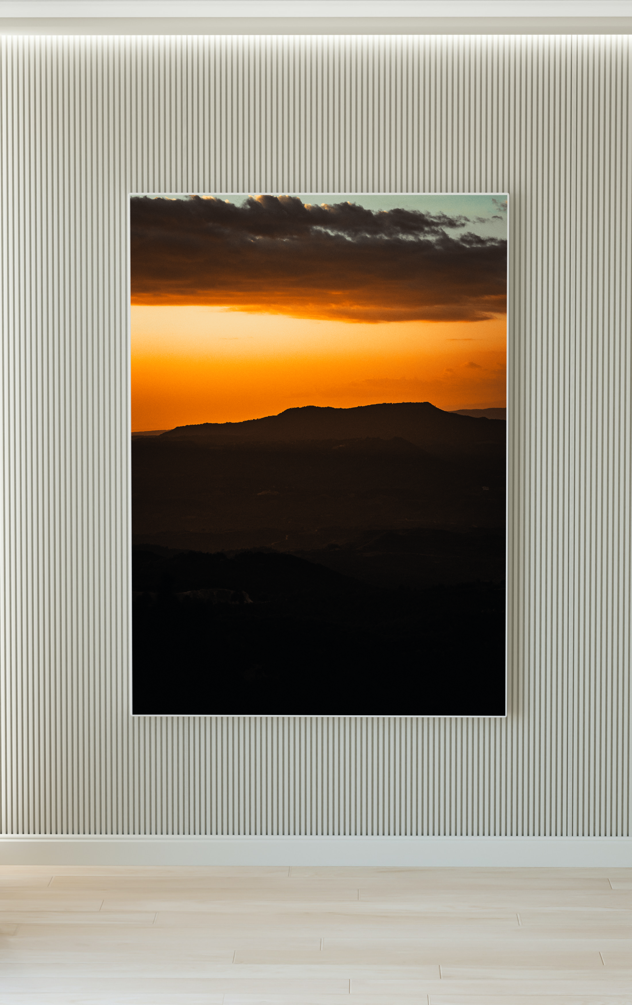 Ventana que muestra un atardecer con cielo naranja y nubes oscuras sobre montañas.