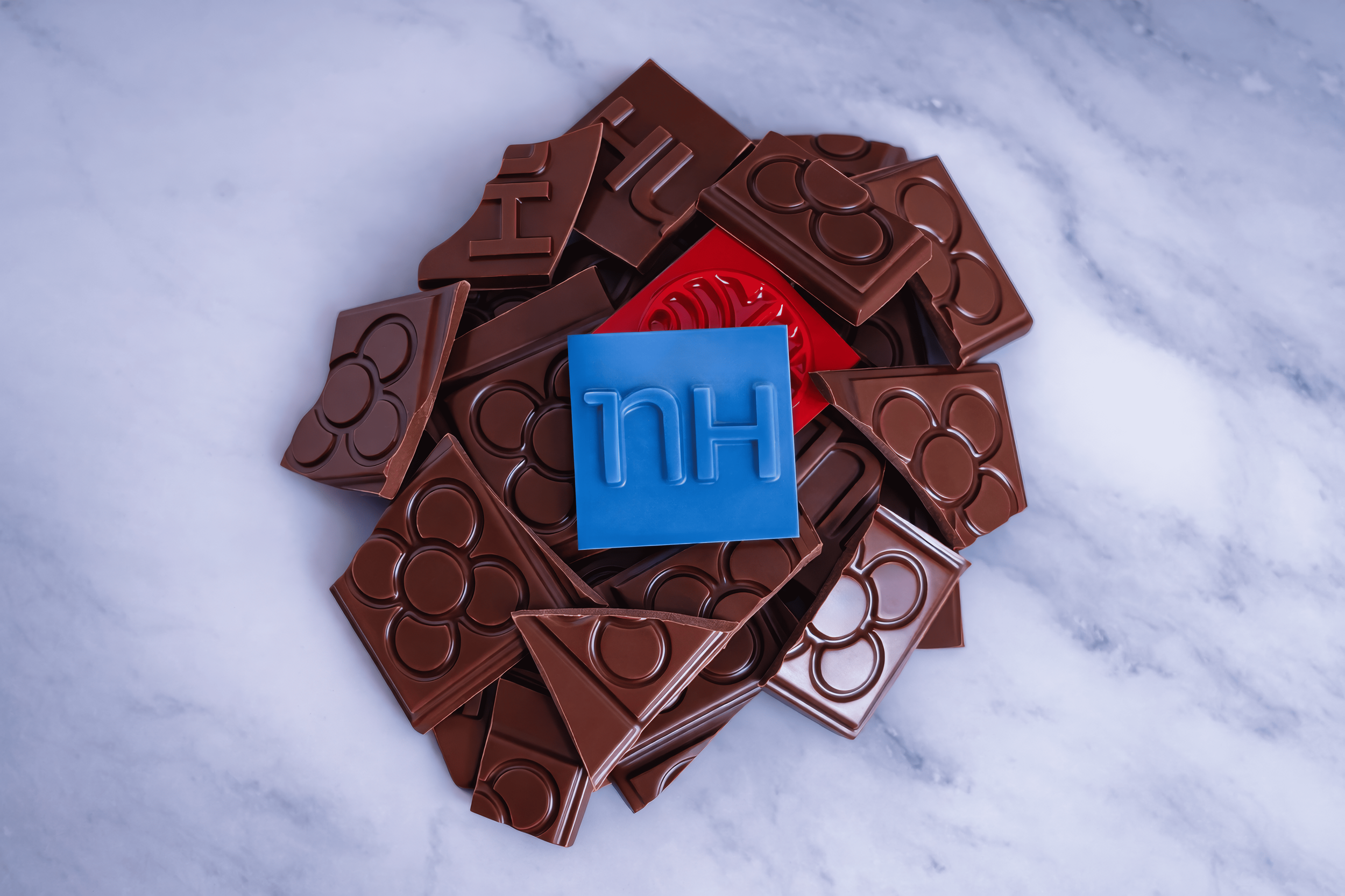 Pedazos de chocolate con letras y un bloque azul con 'H