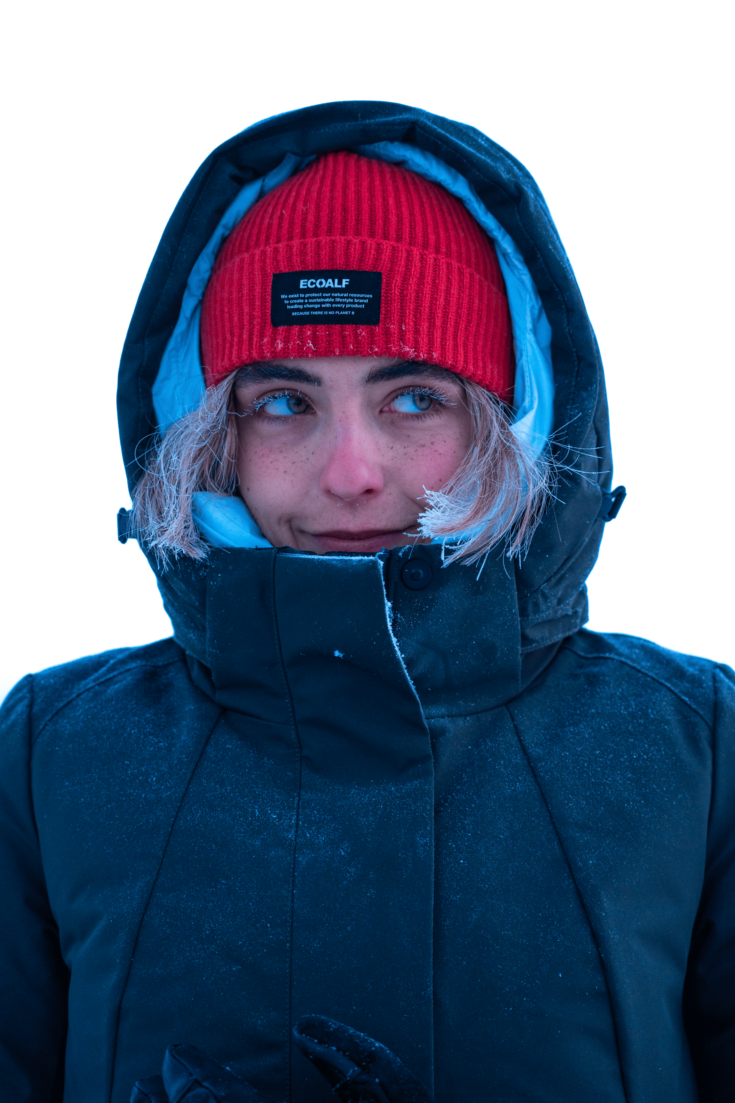 Joven con chaqueta de invierno y gorro rojo, en un entorno nevado, mirando hacia la izquierda con expresión pensativa.