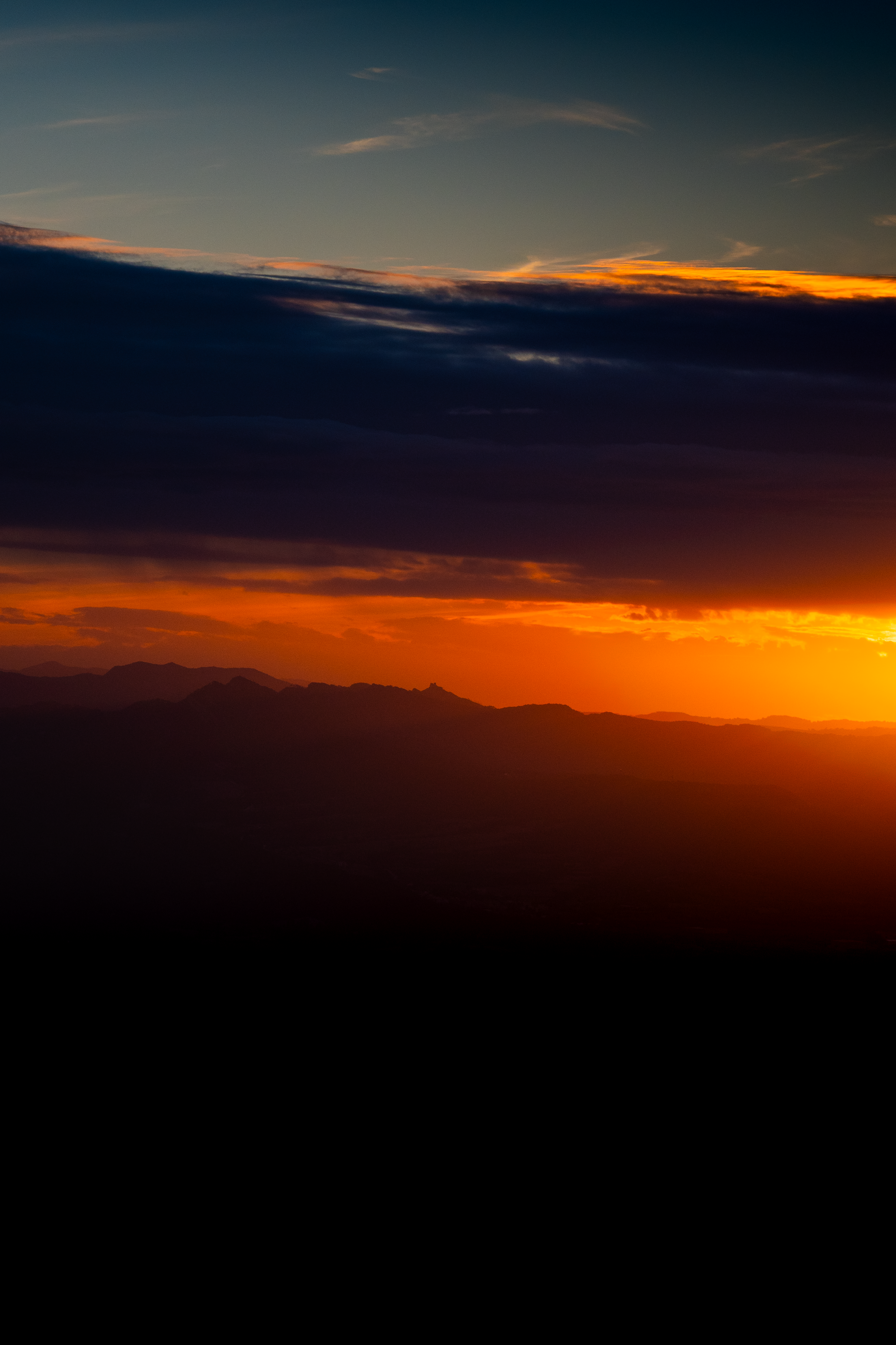 Atardecer con nubes oscuras y cielo naranja en las montañas.