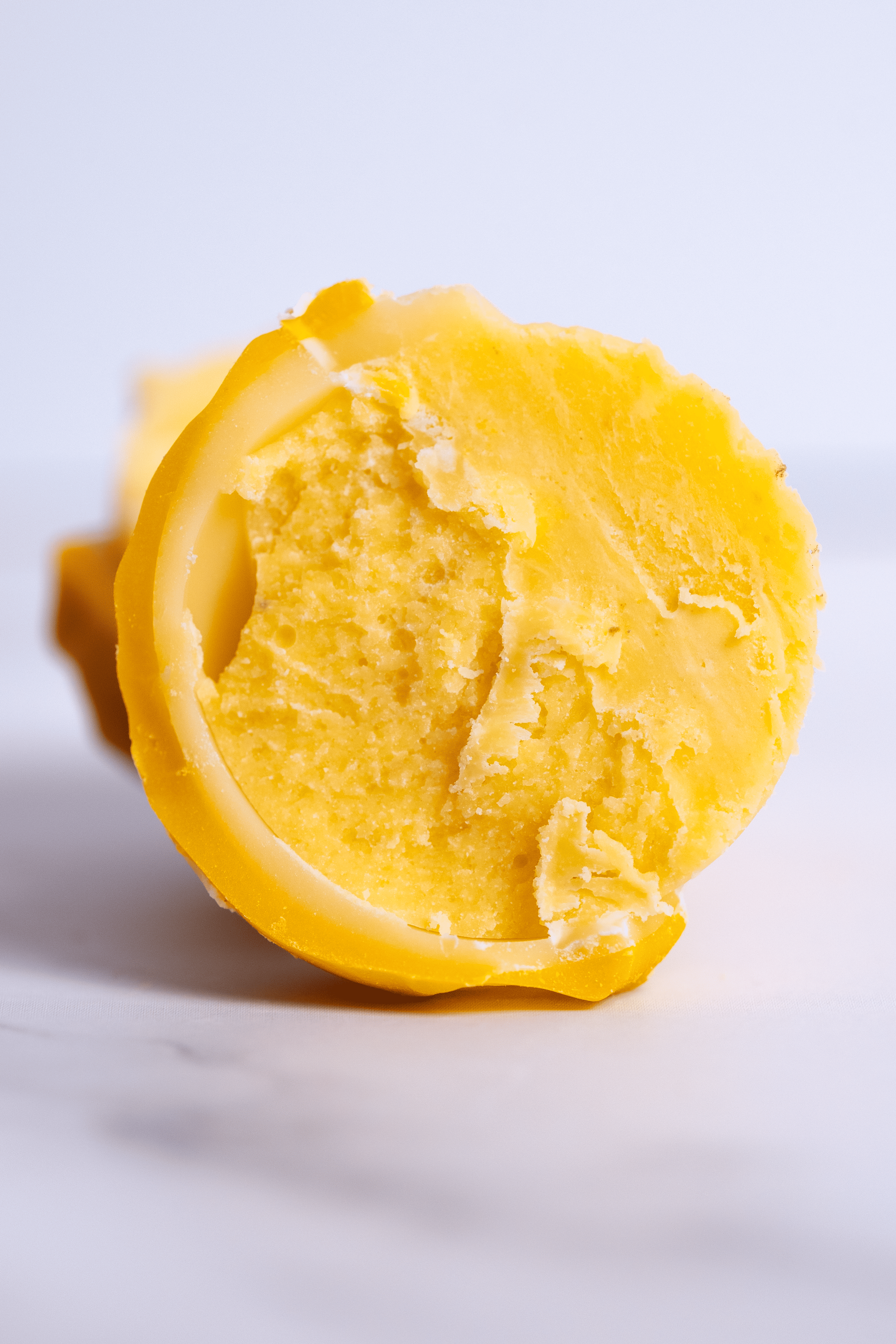 Queso amarillo cortado en rodajas sobre fondo blanco.