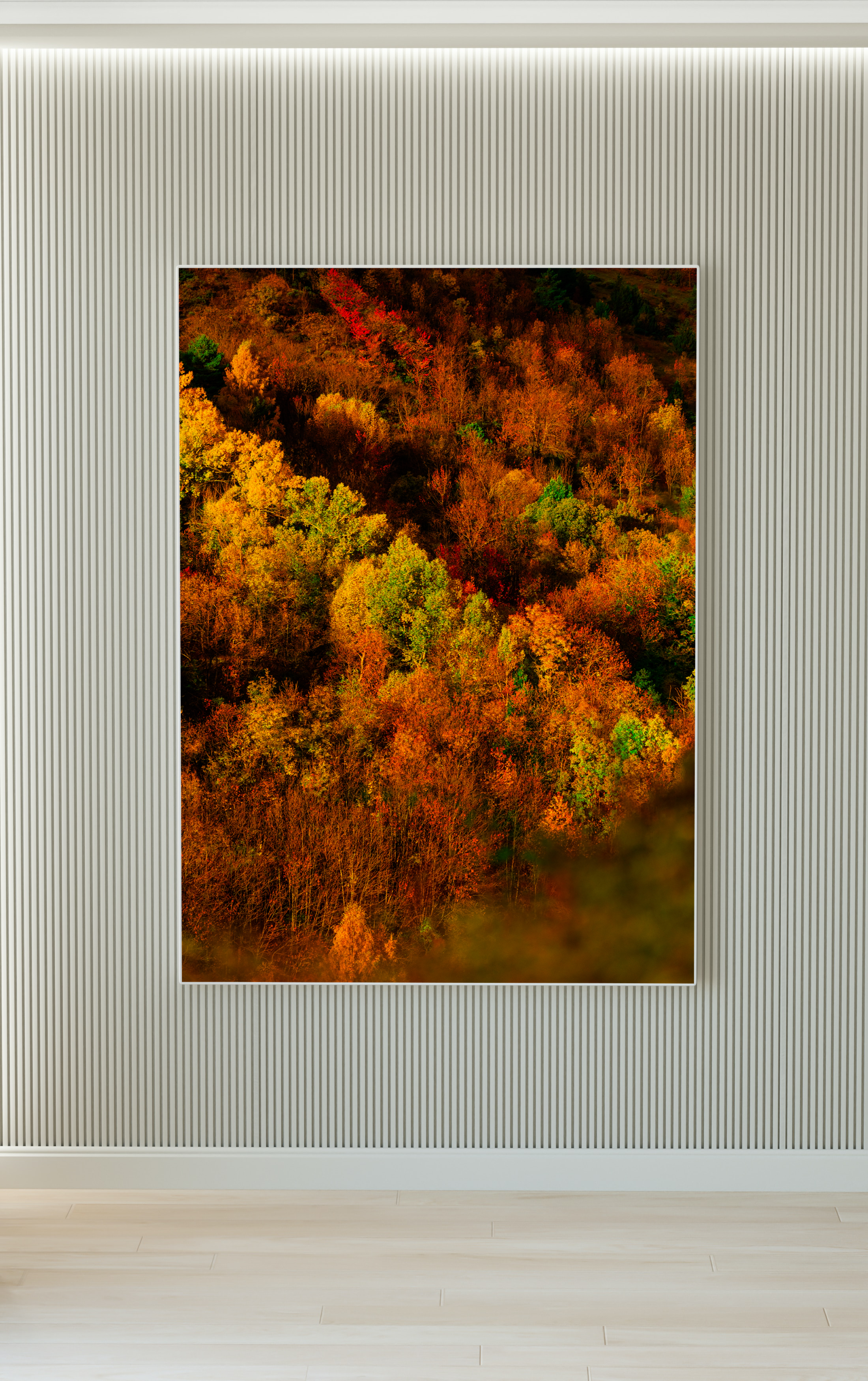 Una pintura o fotografía de un paisaje de bosques con árboles de colores otoñales enmarcada en una pared moderna de tonos grises con texturas verticales.
