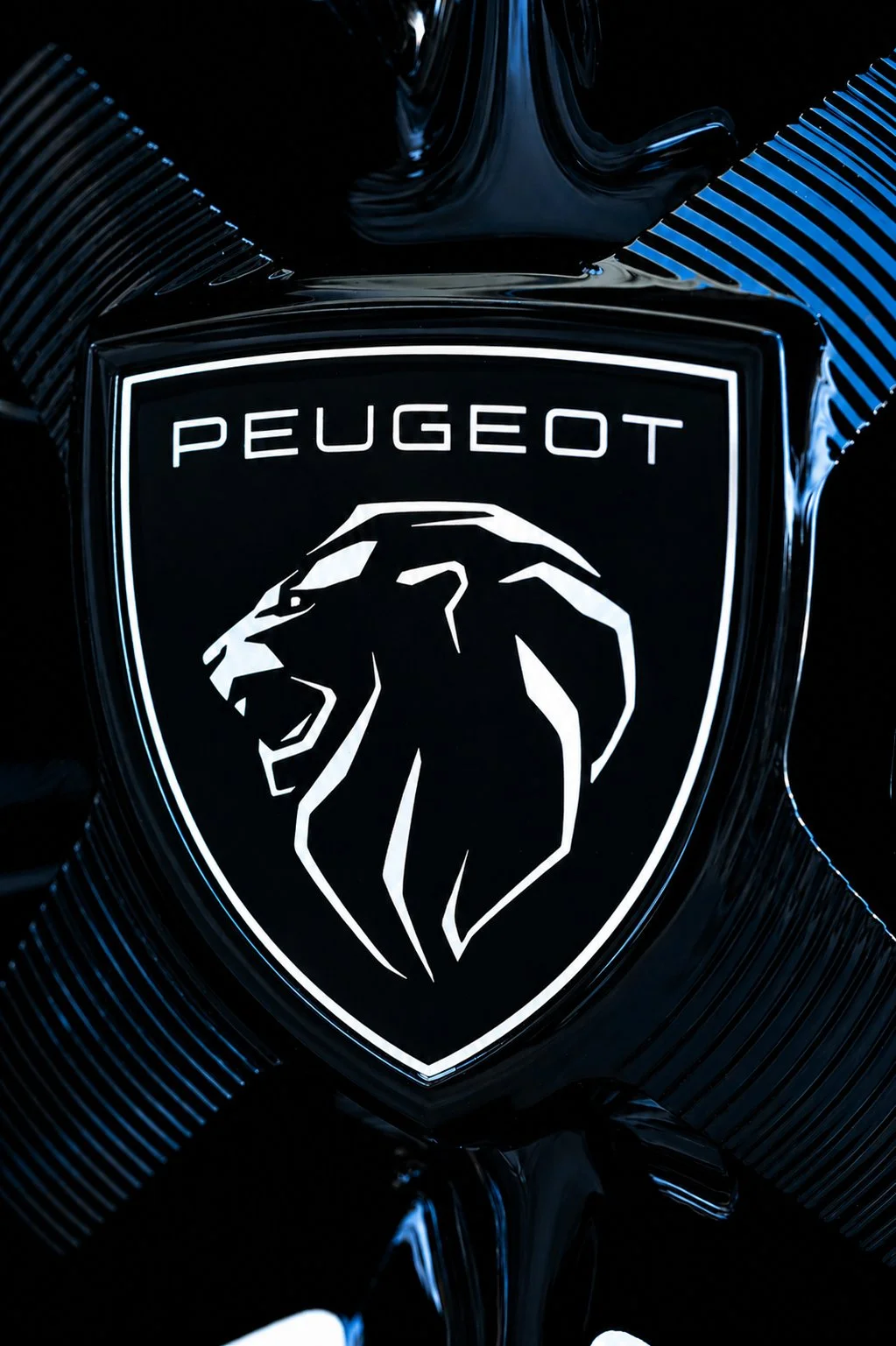 Logotipo de Peugeot con un león en perfil, en tonos negros y blancos sobre fondo oscuro brillante.