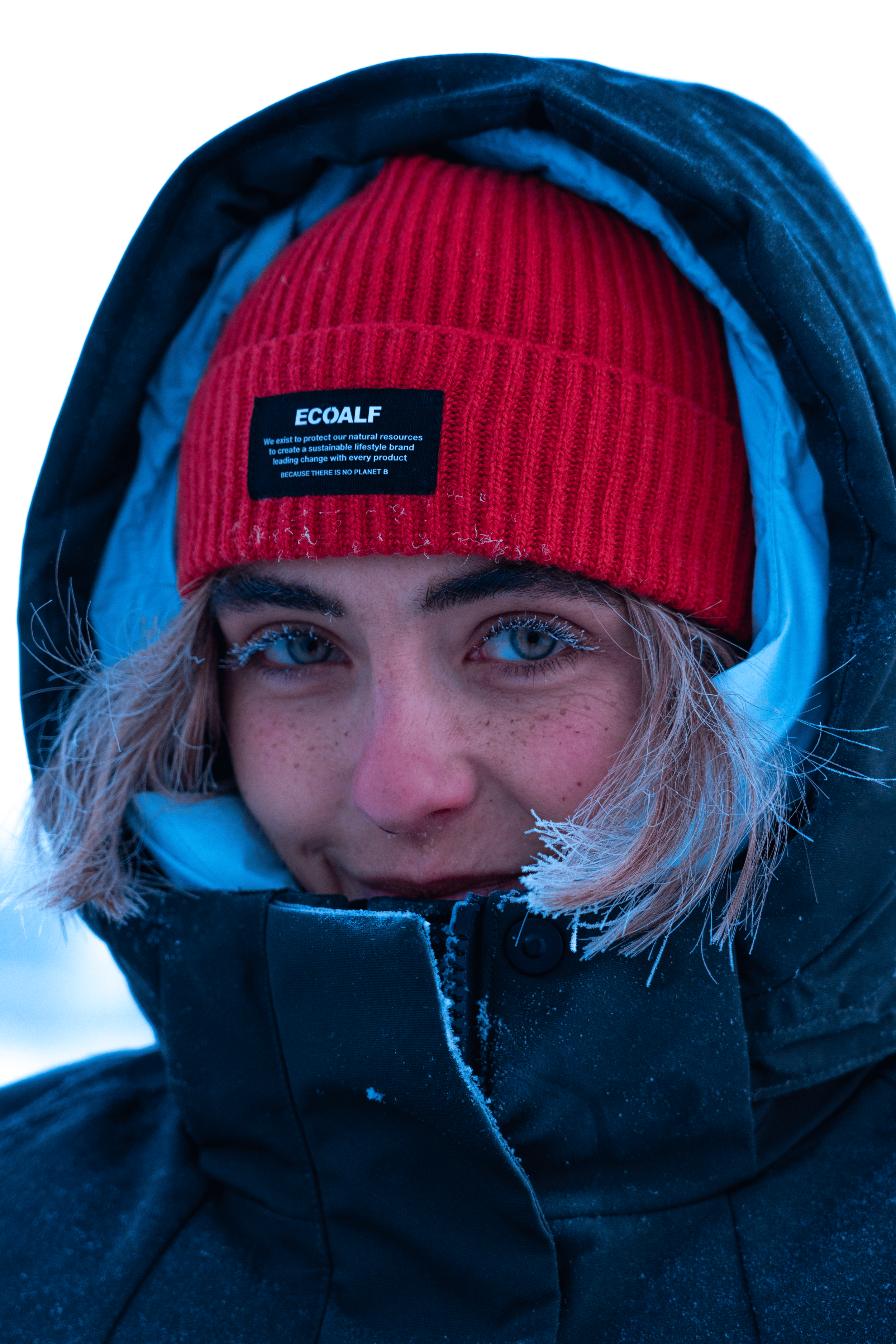 Retrato de una mujer con gorro rojo y chaqueta negra en un entorno invernal.