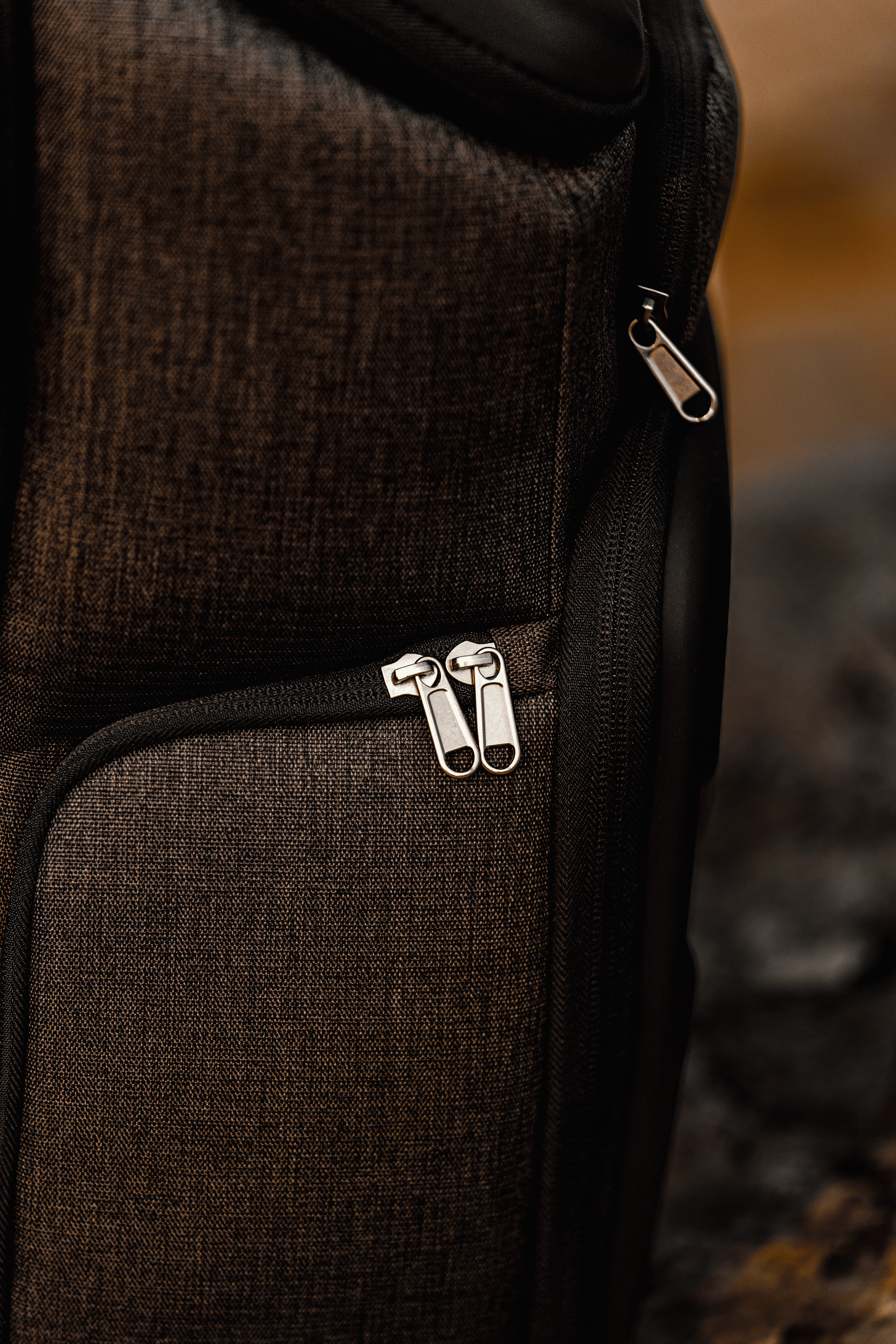 una mochila de color marrón oscuro con cierres plateados, enfocada en un primer plano.
