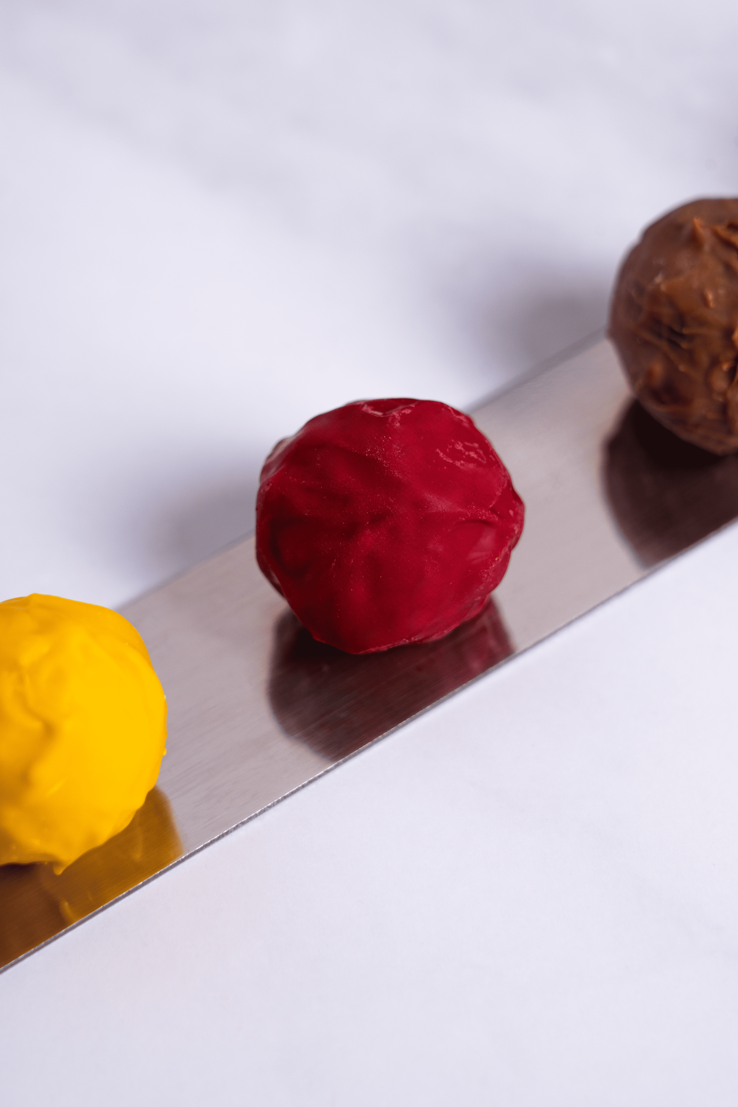 Tres bolas de diferentes colores (amarillo, rojo y marrón) sobre una regla de metal.