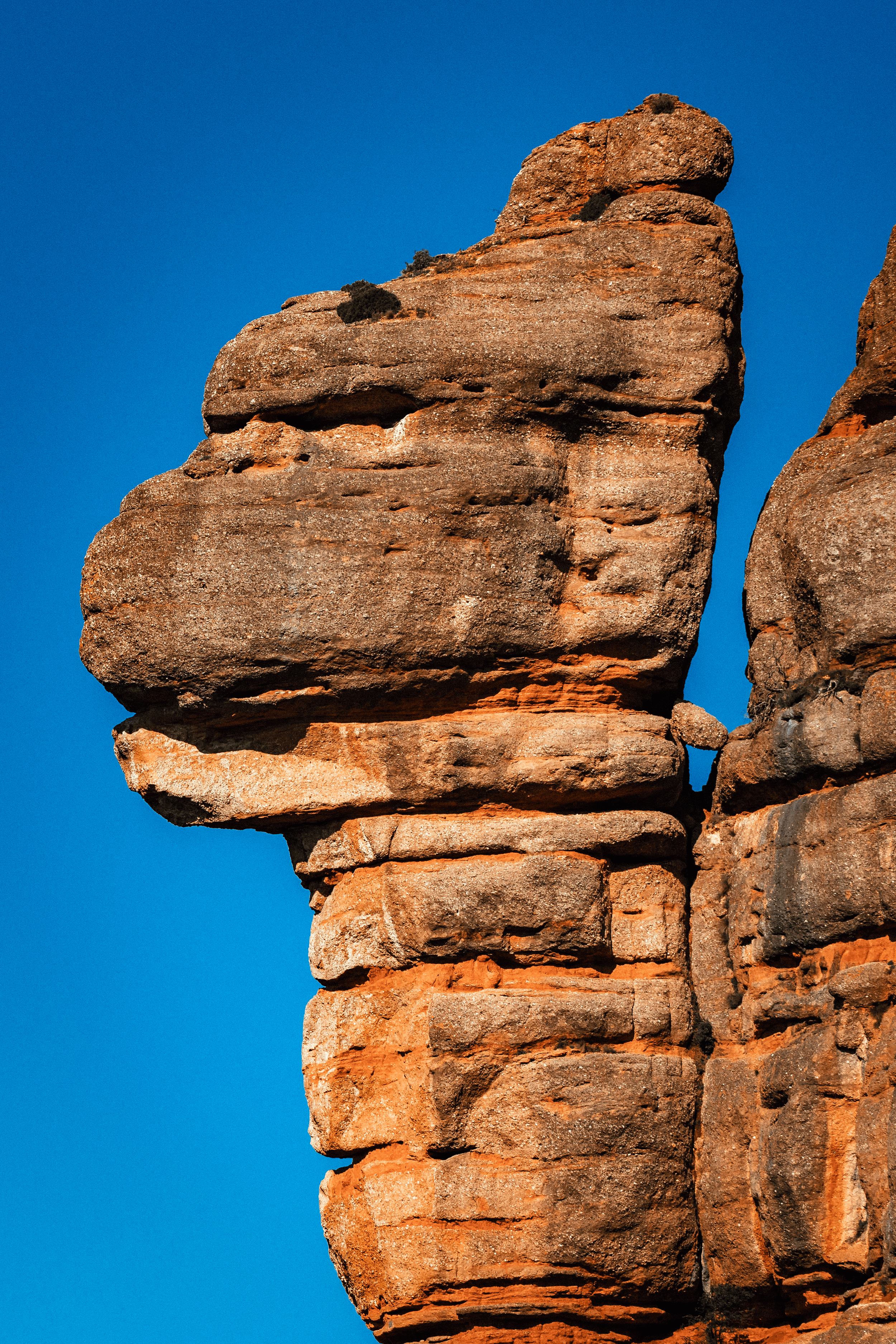 Formaciones rocosas de color marrón anaranjado, con un fondo de cielo azul claro.