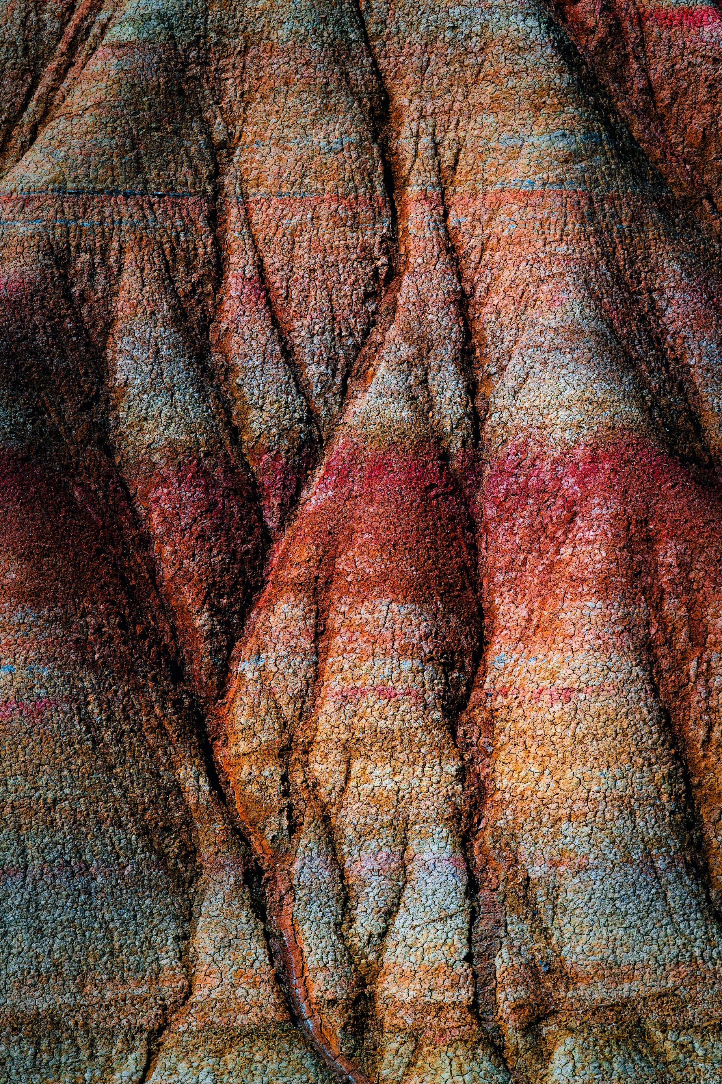 Detalle de la superficie de una roca con texturas ásperas y grietas, con tonos marrones y rojos.
