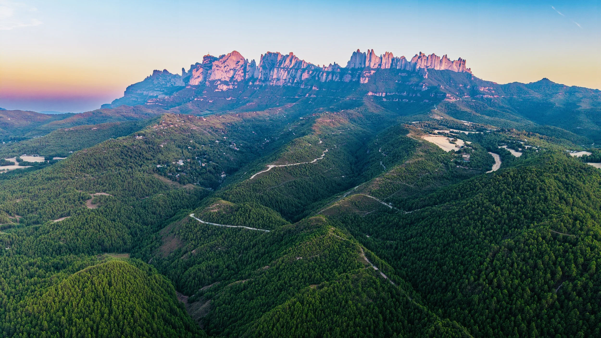 Montañas Rocosas con picos rojos al atardecer y bosques verdes en las pendientes.