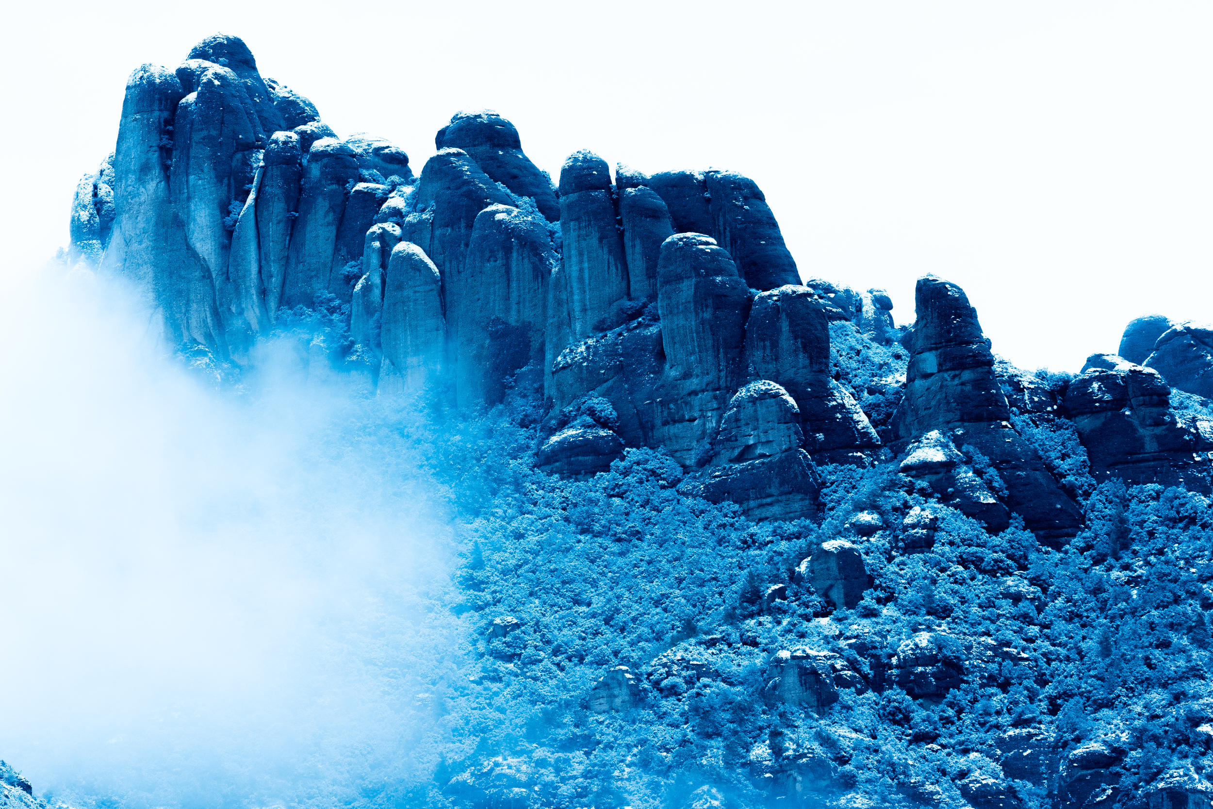Montaña rocosa cubierta de nieve con niebla en la parte inferior y al fondo el cielo