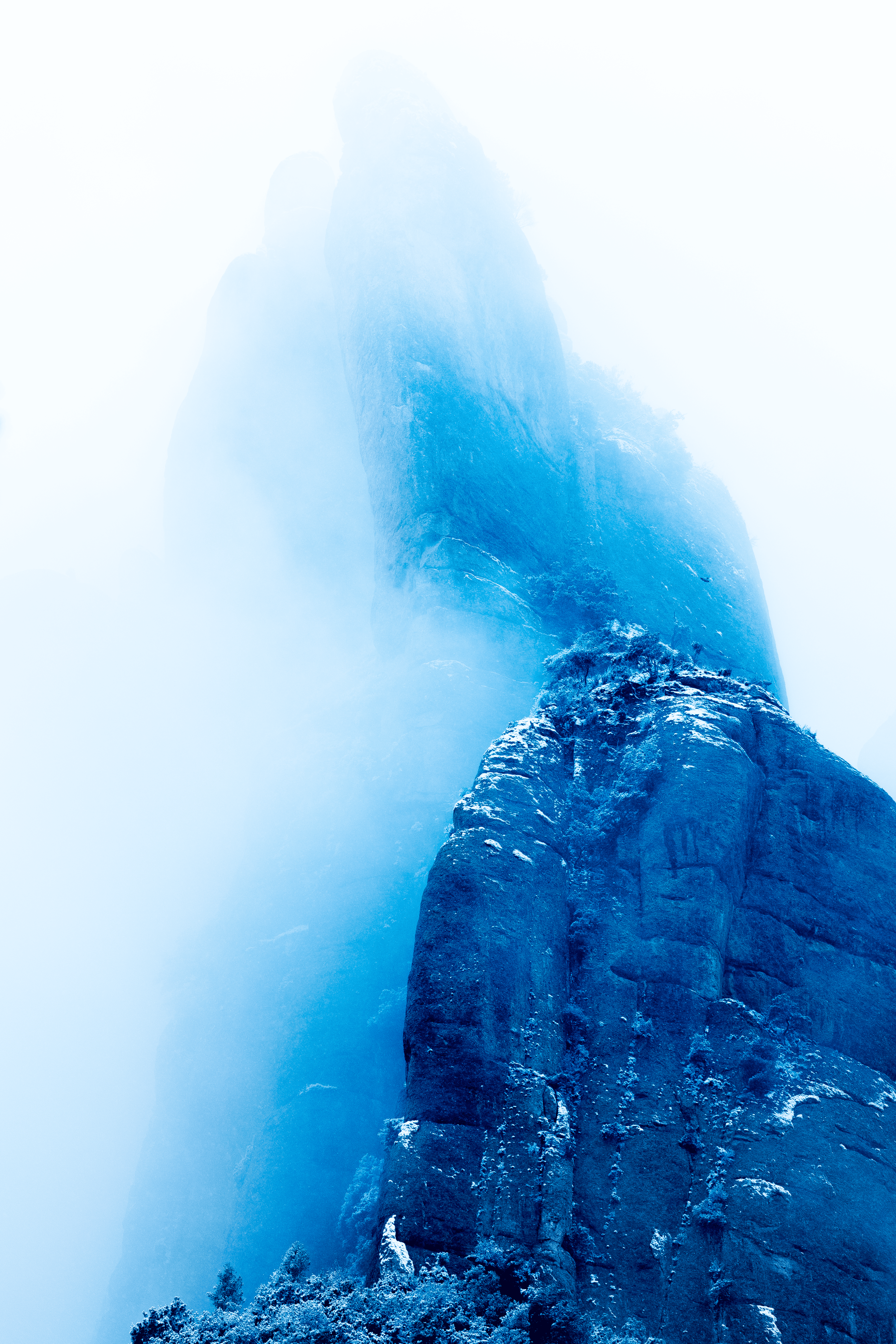 Montañas cubiertas de neblina con vegetación en la base, en tonalidades azules.
